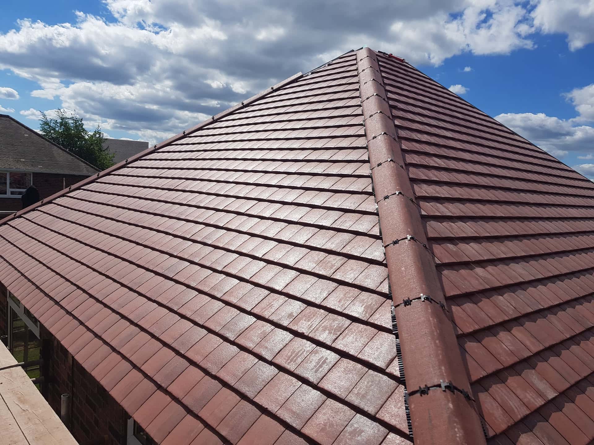 Completed pitched roof with brown concrete tiles and dry ridge system