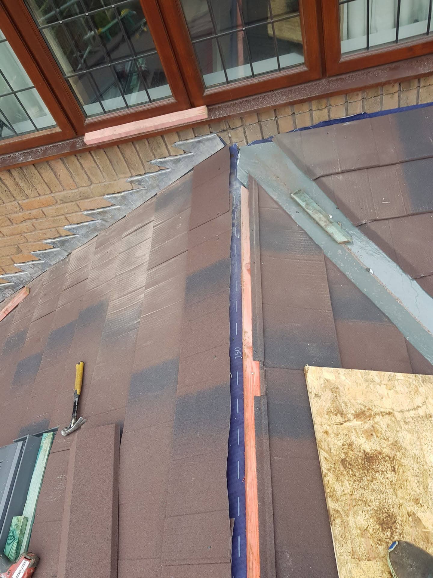 Pitched roof with brown concrete tiles, lead valley and ridge flashing detail