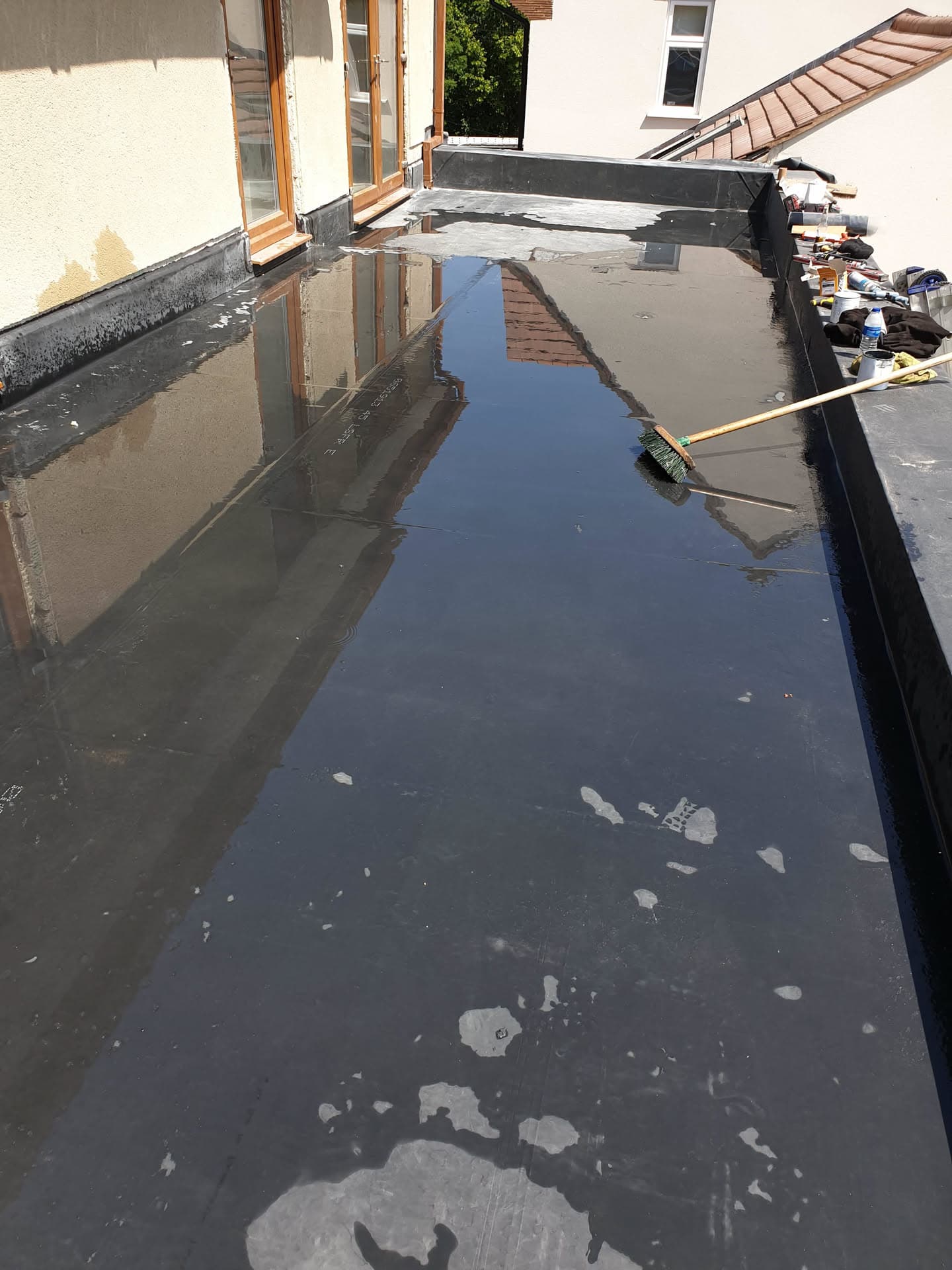 Flat roof with dark grey EPDM rubber membrane and lead flashing around dormer window