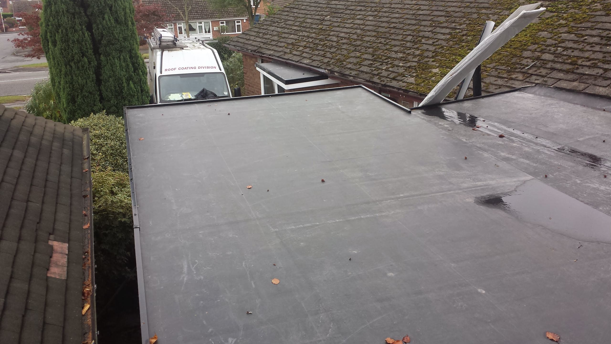 Grey flat roof with EPDM rubber membrane between tiled pitched roofs
