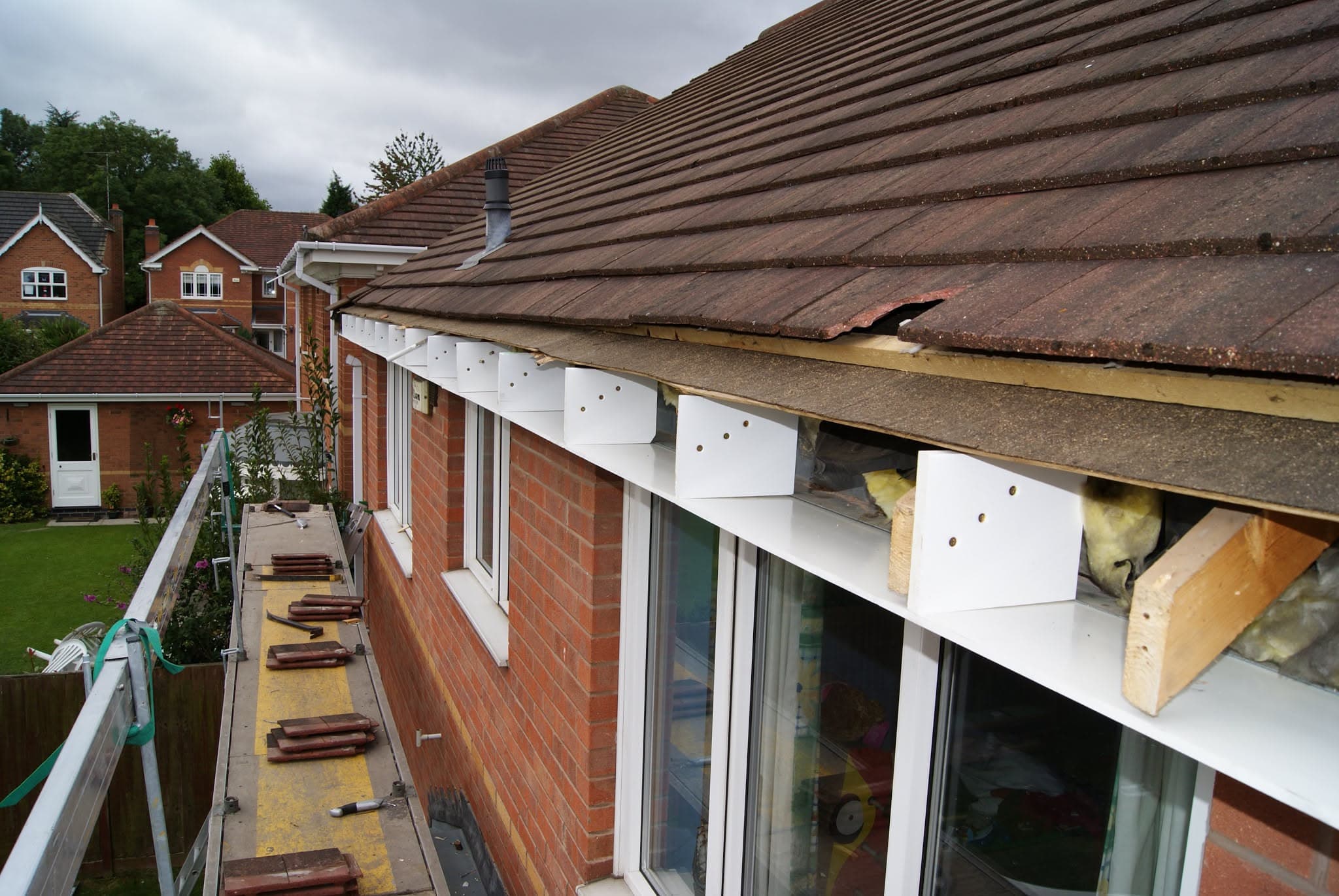 Pitched concrete tiled roof with exposed fascia boards and insulation during repair work