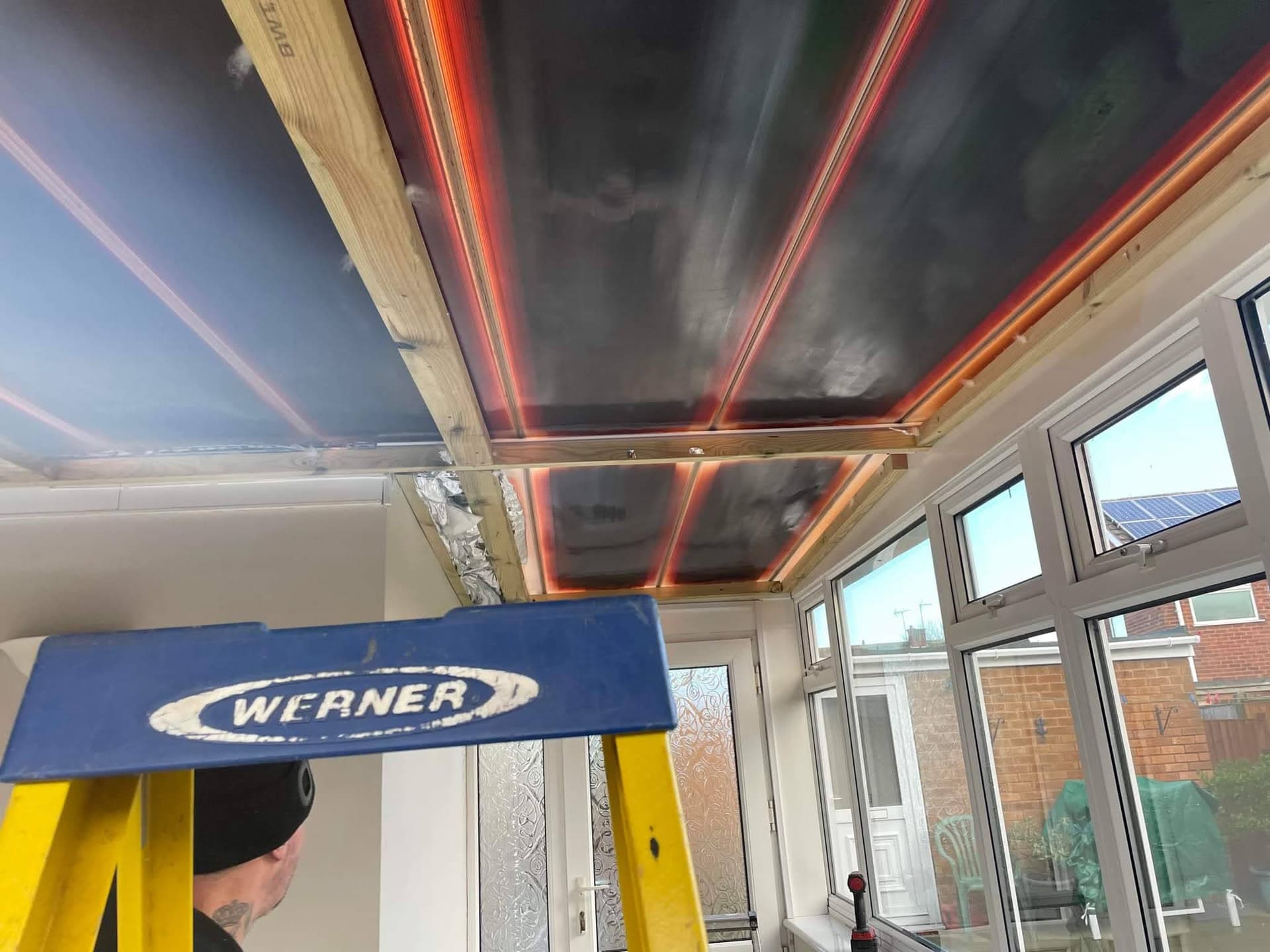 Interior view of conservatory roof installation with exposed timber framework and dark membrane