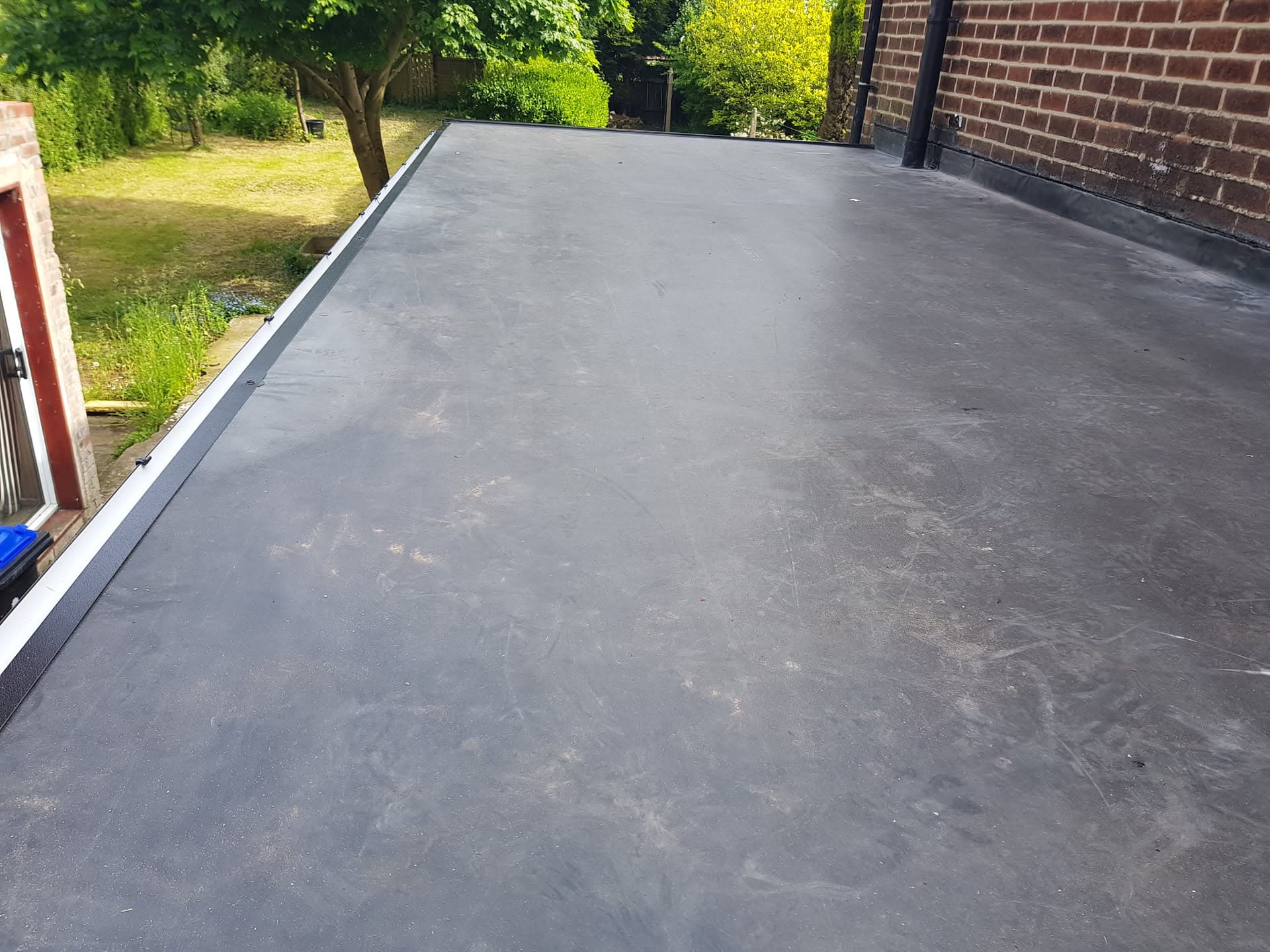 Completed flat roof with dark grey EPDM rubber membrane and white trim edging