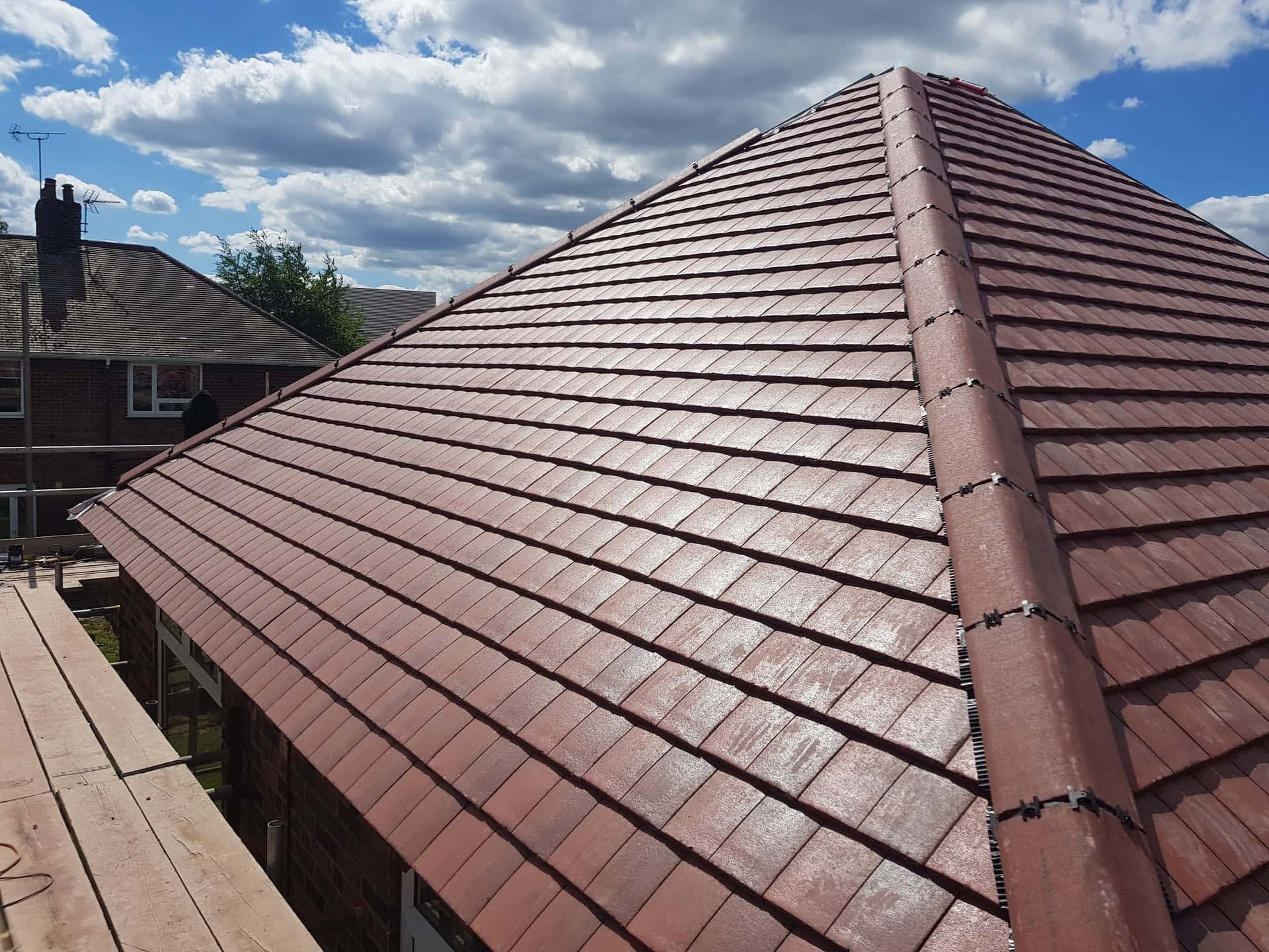 Newly completed pitched roof with brown concrete tiles and ridge tiles