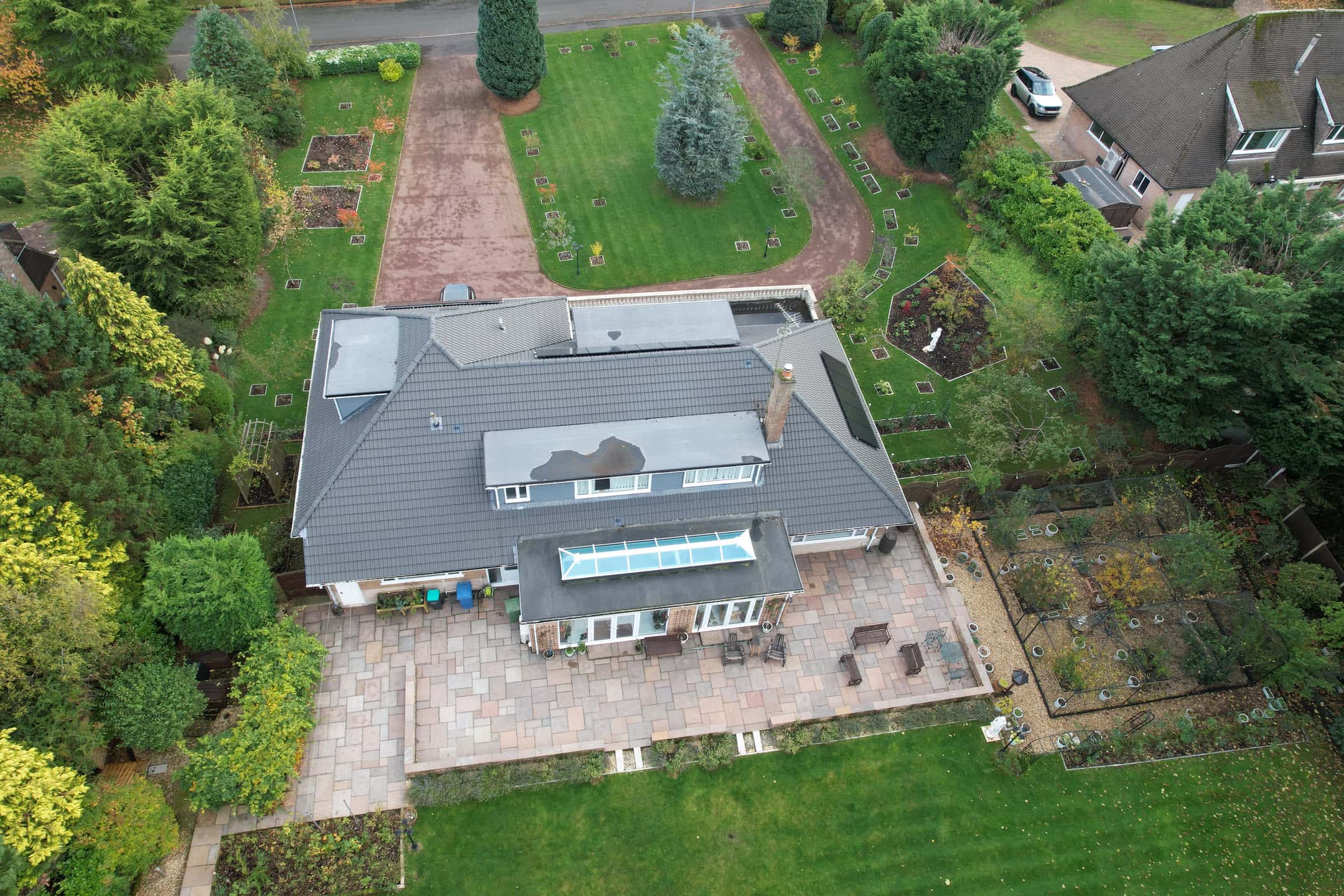 Aerial view of residential property with grey tiled pitched roof and conservatory extension