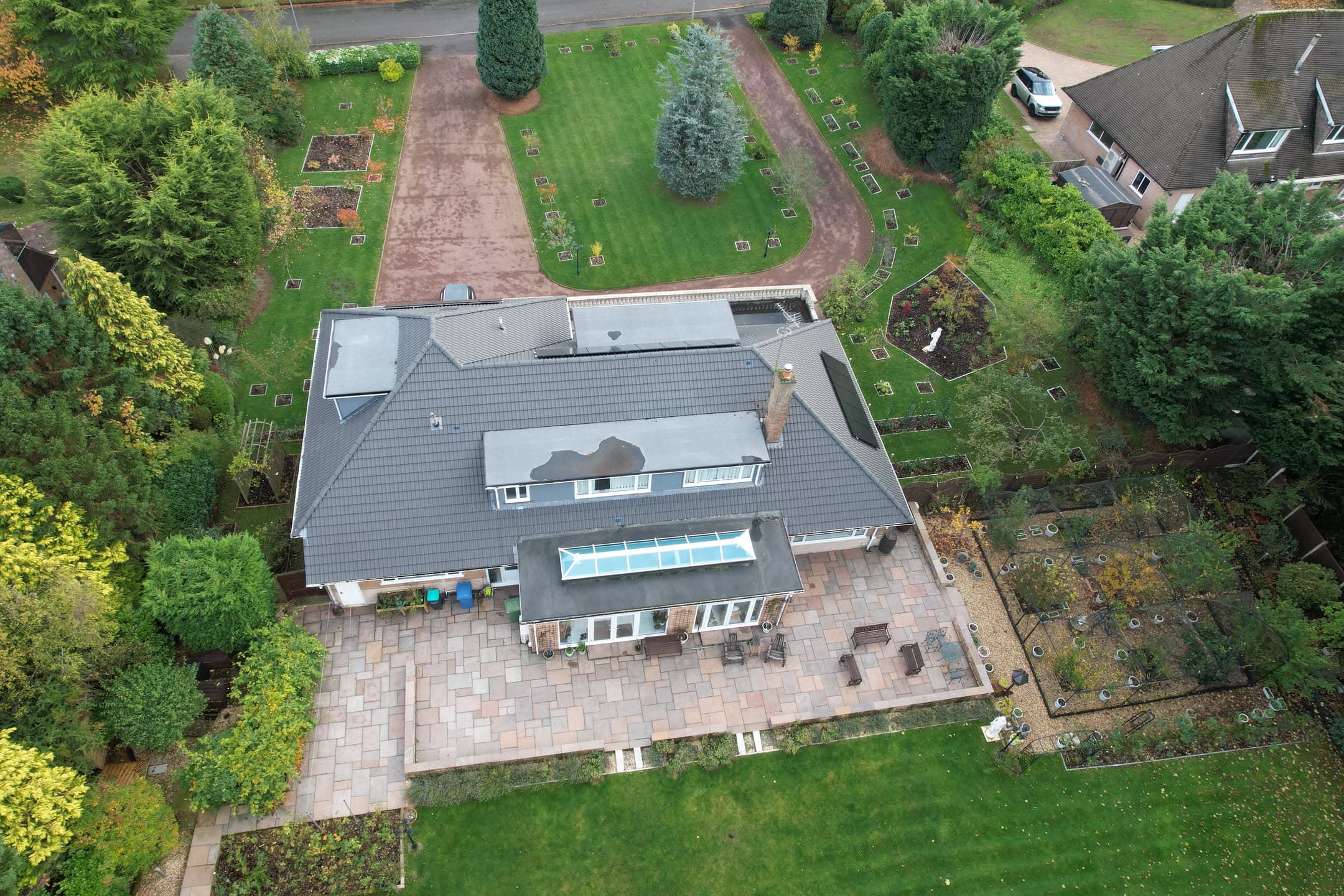 Aerial view of residential property with grey tiled pitched roof and conservatory extension
