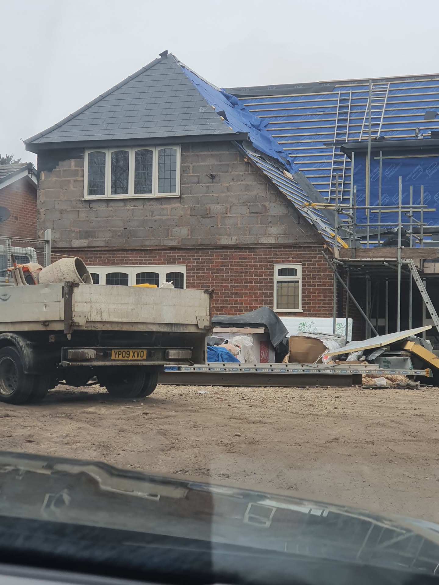 Pitched roof re-roofing in progress with grey slate tiles and exposed roof battens