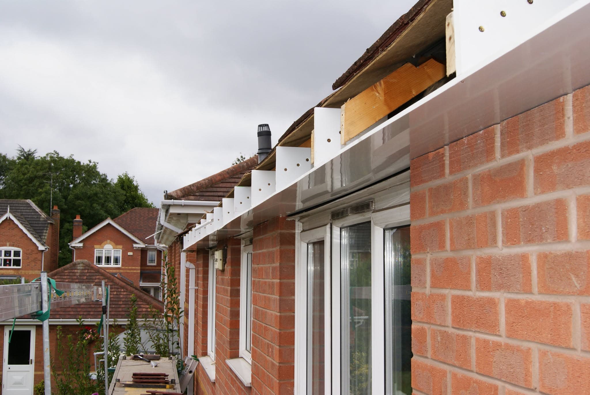 Pitched tiled roof with white fascias and soffits on red brick house