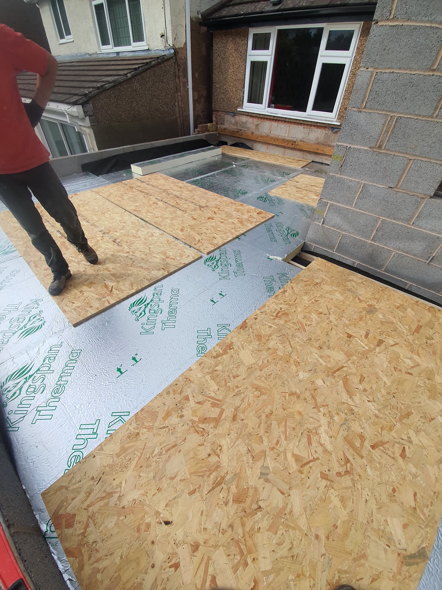 Flat roof installation in progress with insulation boards and OSB decking being laid
