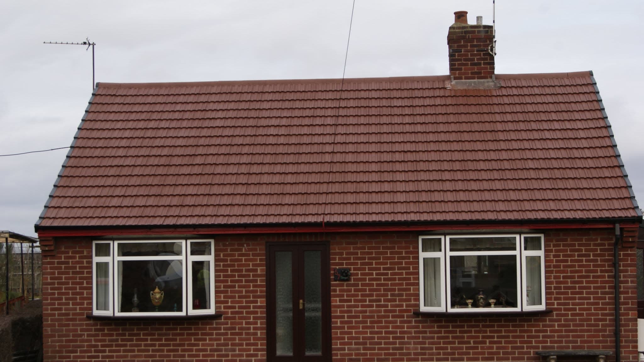 Red-brown tiled pitched roof on brick bungalow with chimney stack