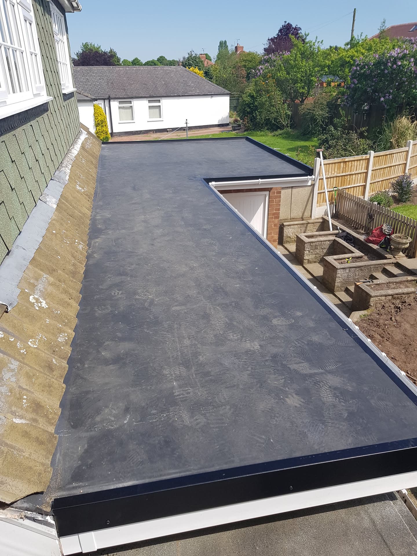 Completed flat roof extension with dark grey EPDM rubber membrane and white fascia trim