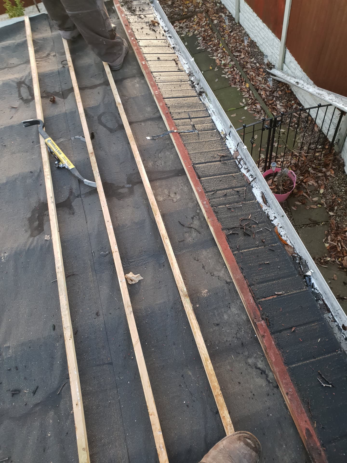 Flat roof with timber battens being installed over felt membrane by fitter