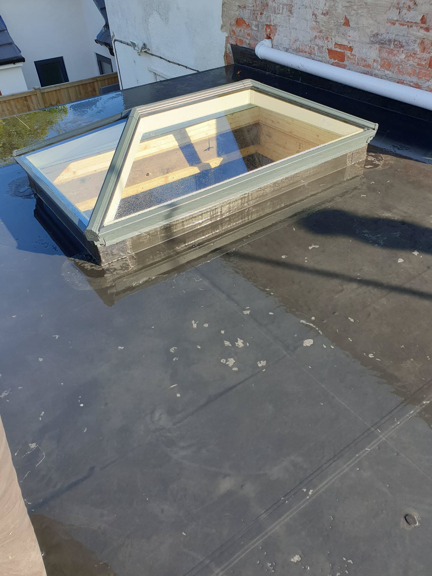Flat roof with skylight and dark rubber membrane between brick walls