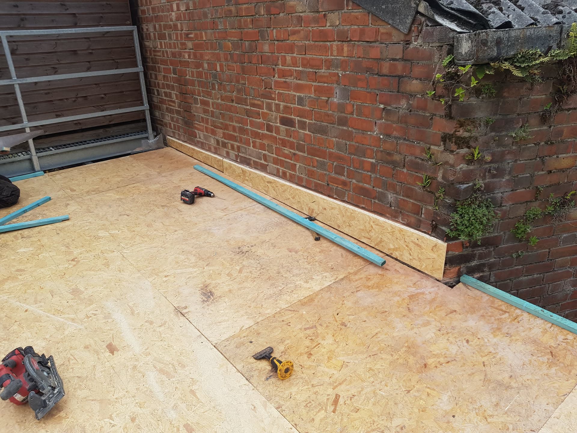 Flat roof installation with OSB decking boards and blue battens in progress
