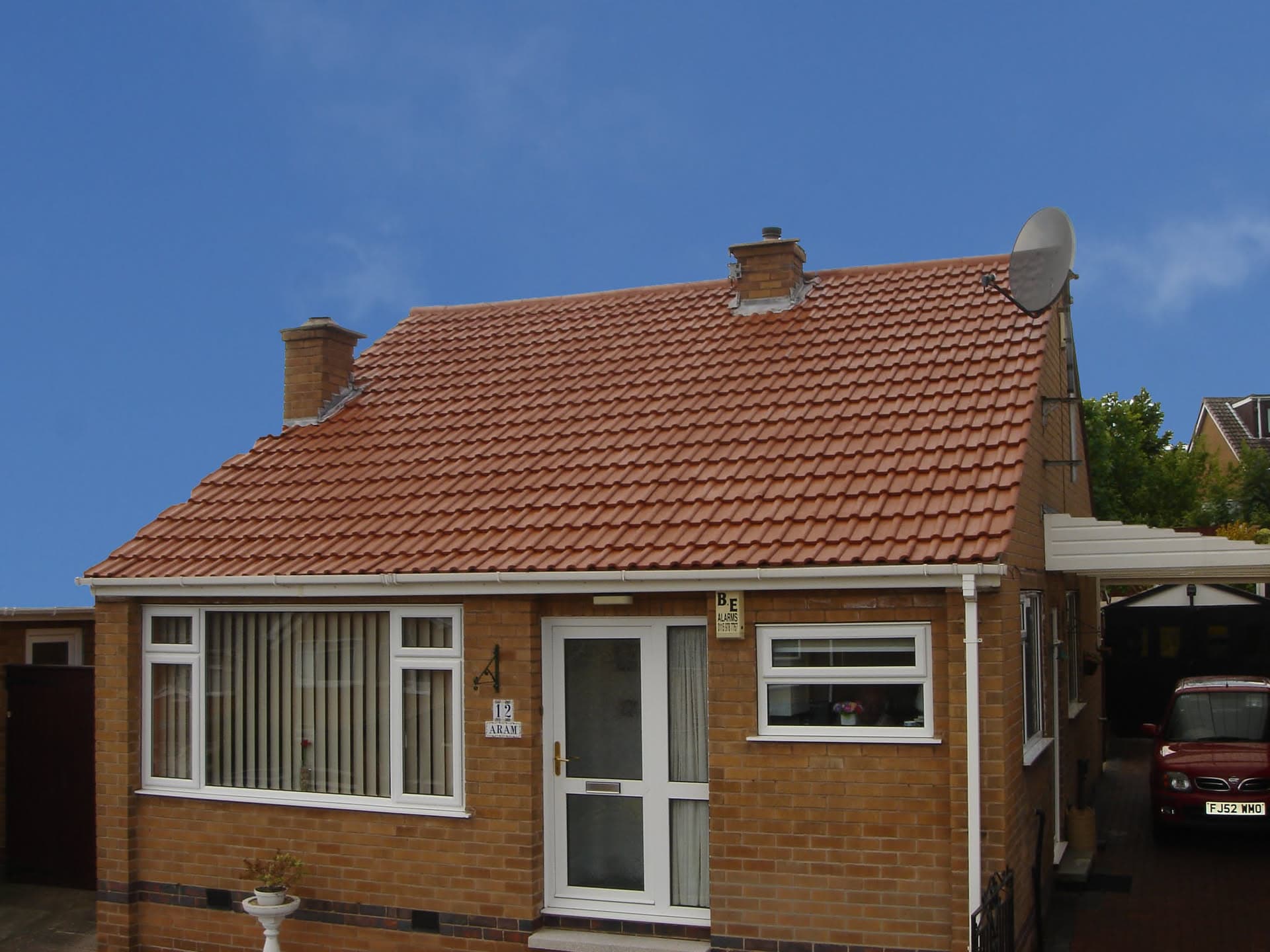 Pitched roof with red clay tiles and two brick chimney stacks