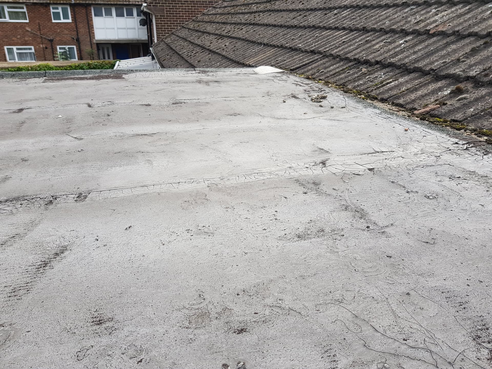 Weathered flat roof with felt covering showing signs of wear and cracking