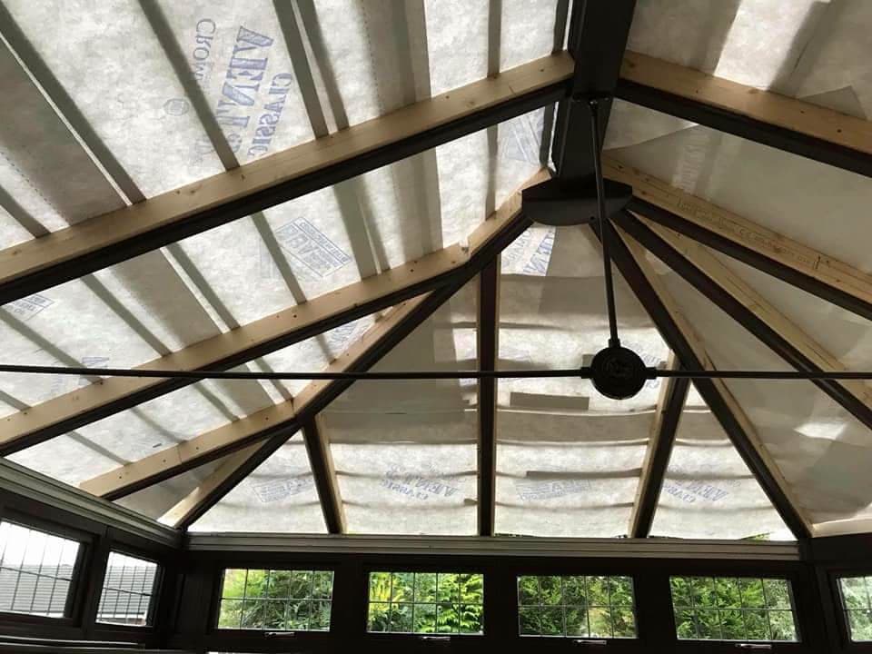Interior view of conservatory roof structure with timber rafters and translucent roofing panels