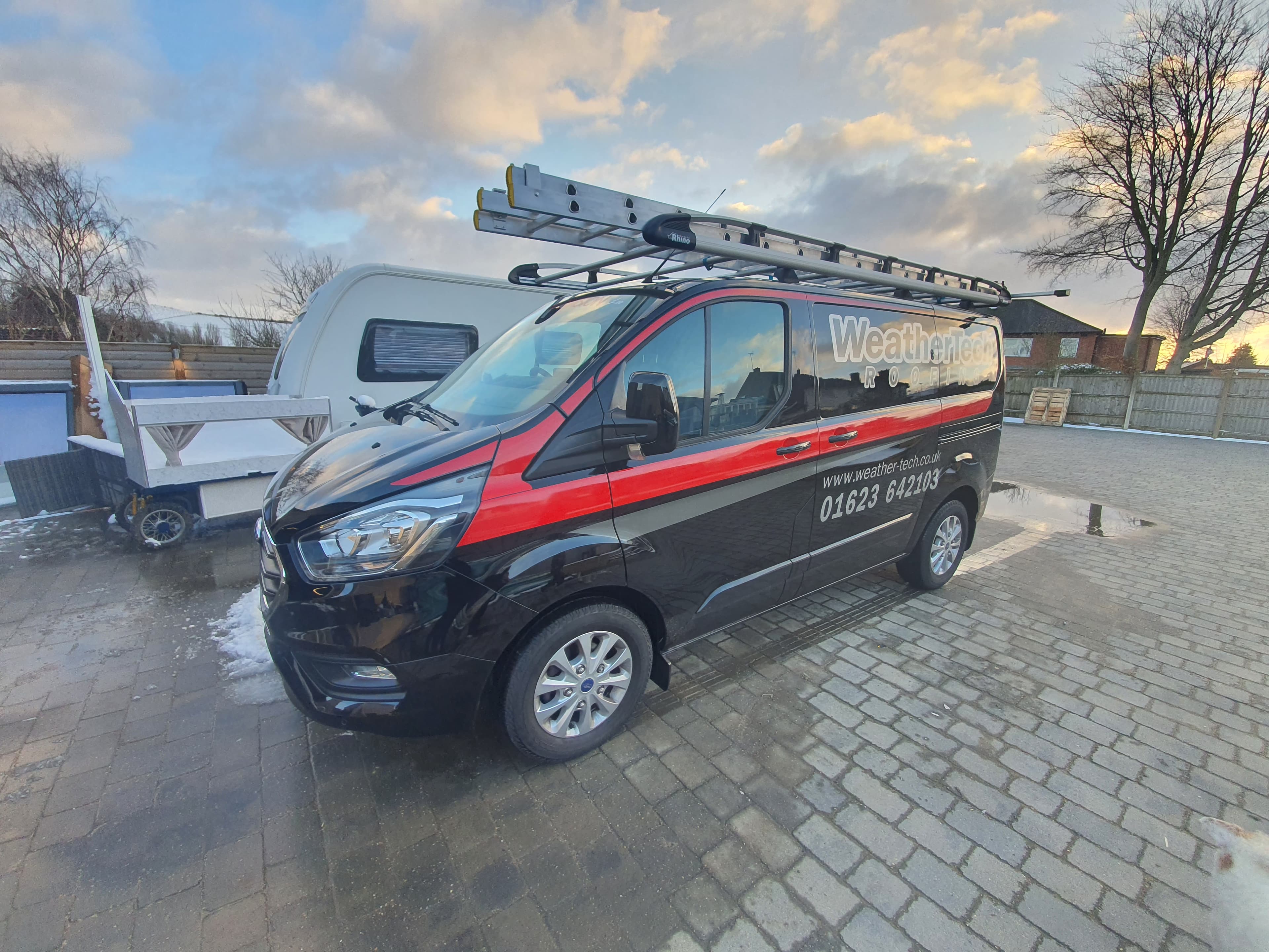 WeatherTech Roofing company van with roof ladder parked on block paved driveway