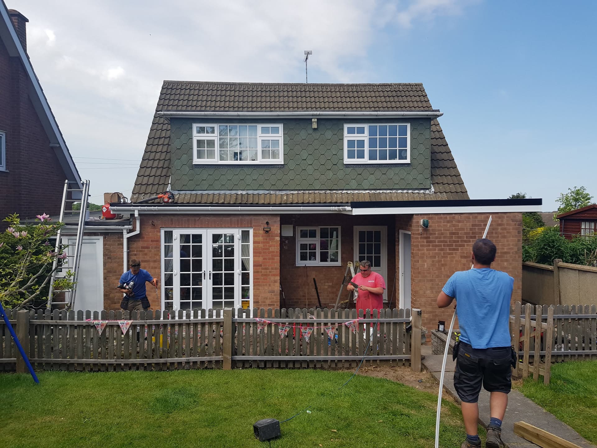 Pitched roof with dark brown concrete tiles and dormer windows with white fascias and guttering