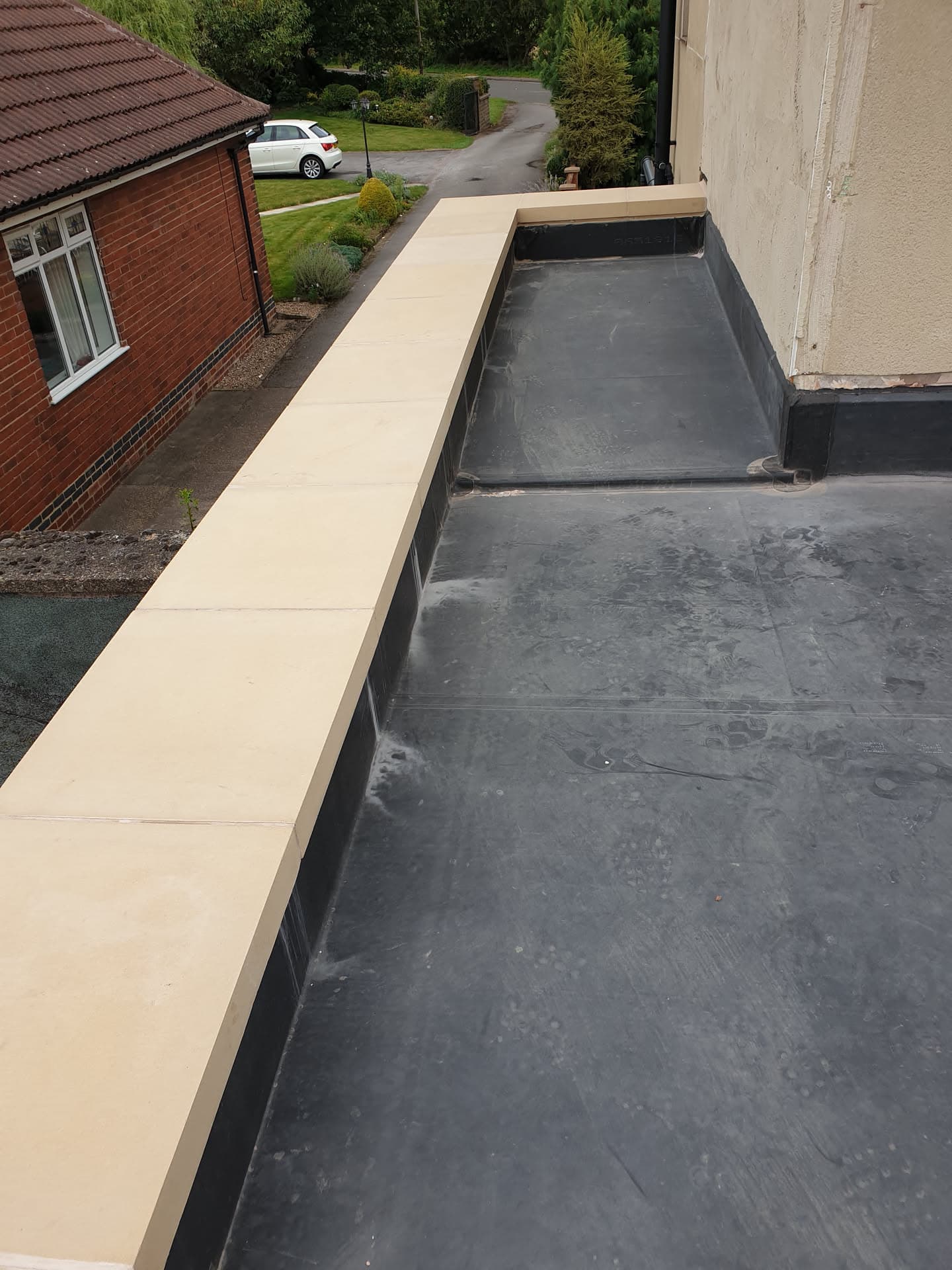 Flat roof with grey EPDM rubber membrane and cream fascia boards on residential property