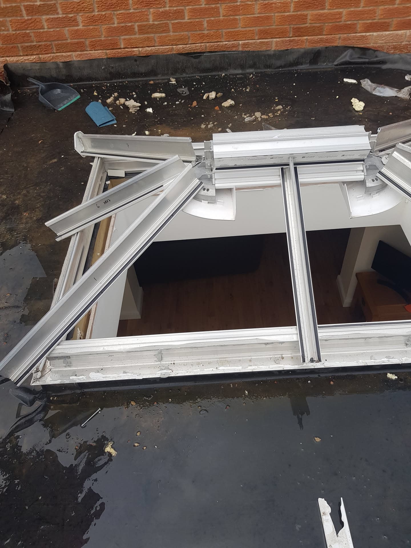 Flat roof with white conservatory roof frame being installed on dark felt surface