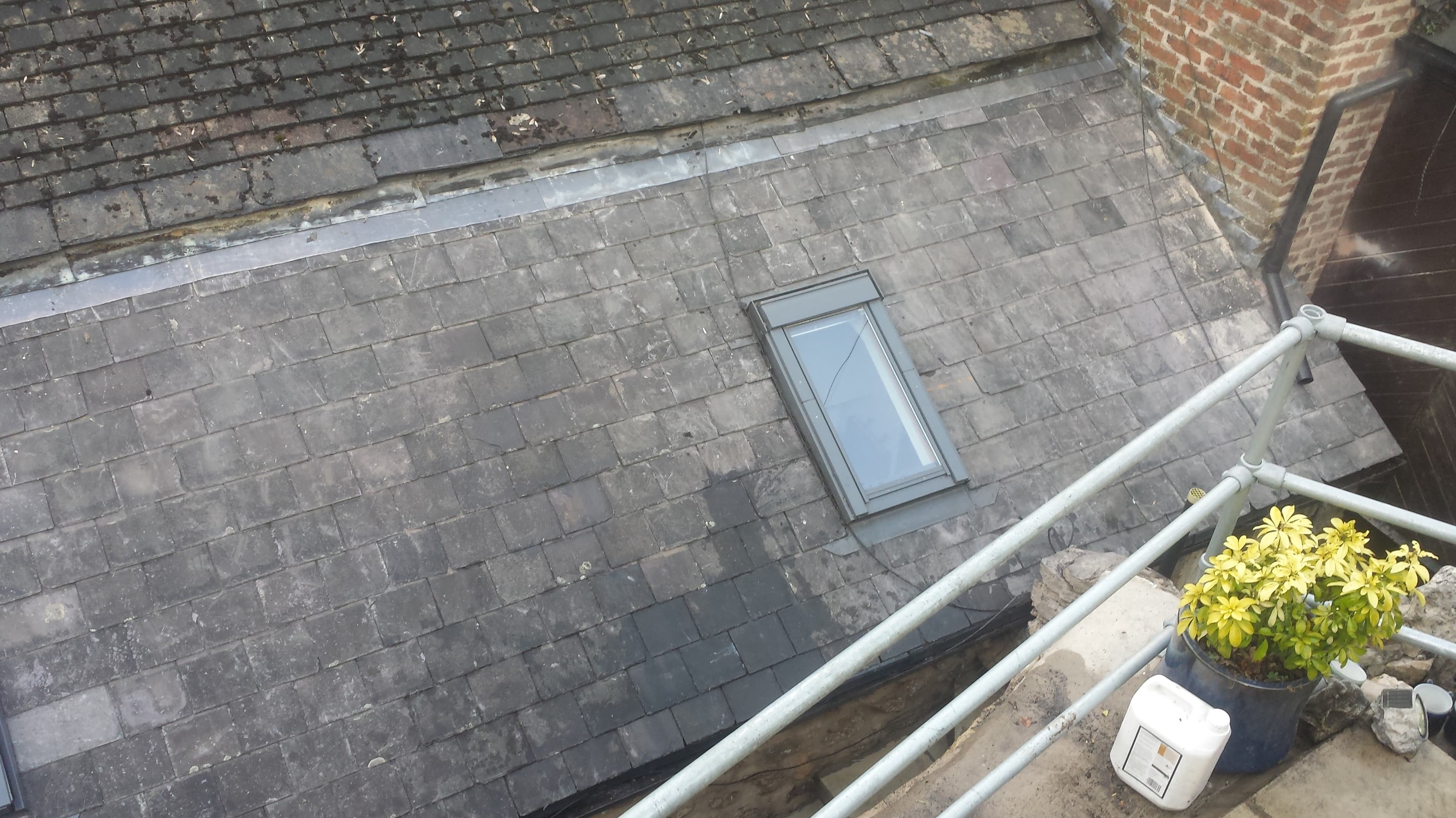 Pitched slate roof with skylight window and brick chimney stack