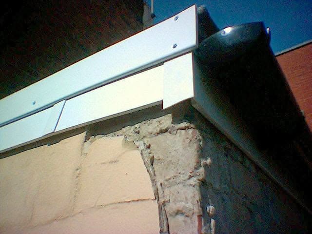 White fascia board and black guttering installed on flat roof edge