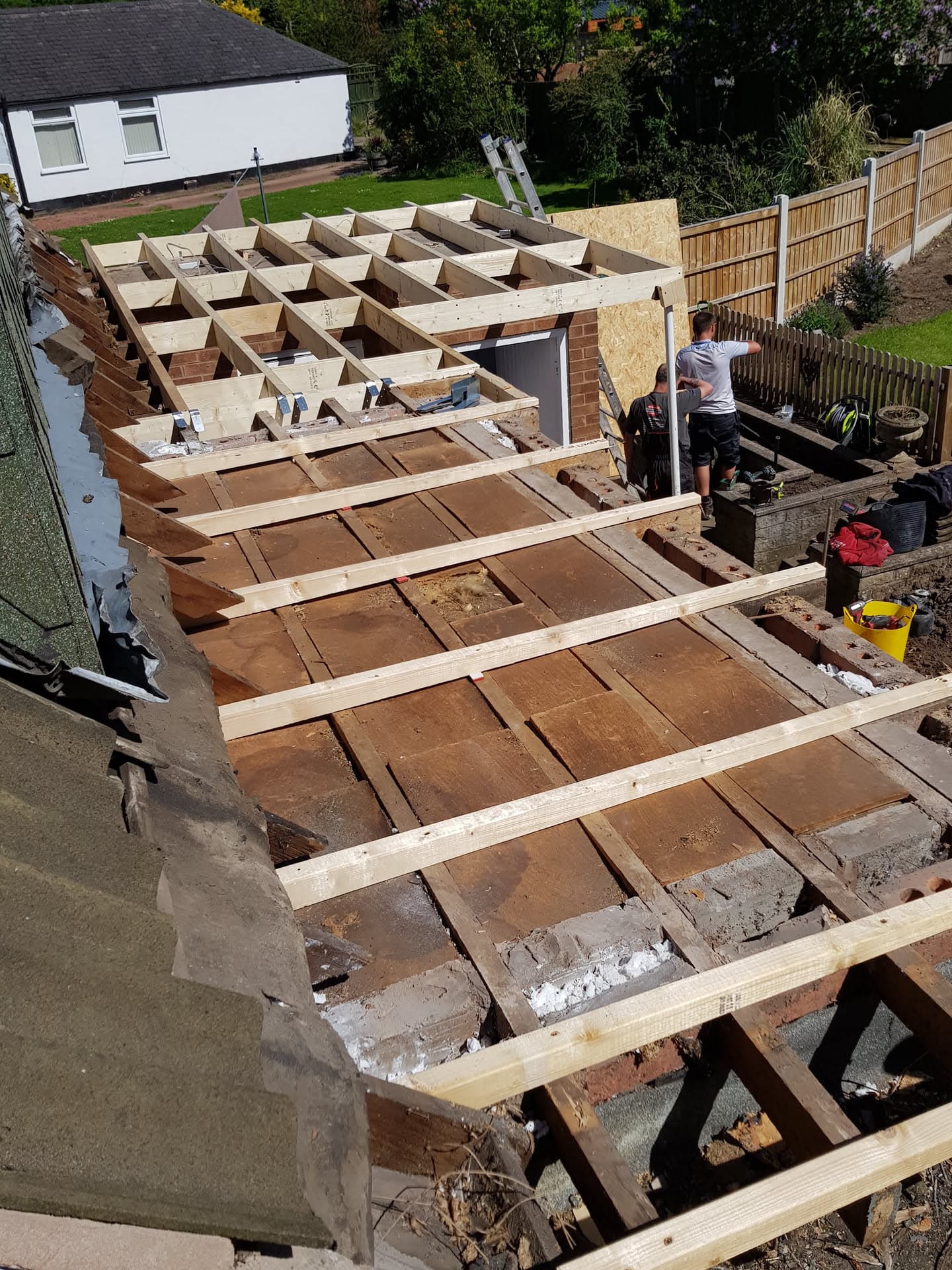 Flat roof replacement in progress with new timber joists and insulation boards being installed by fitters