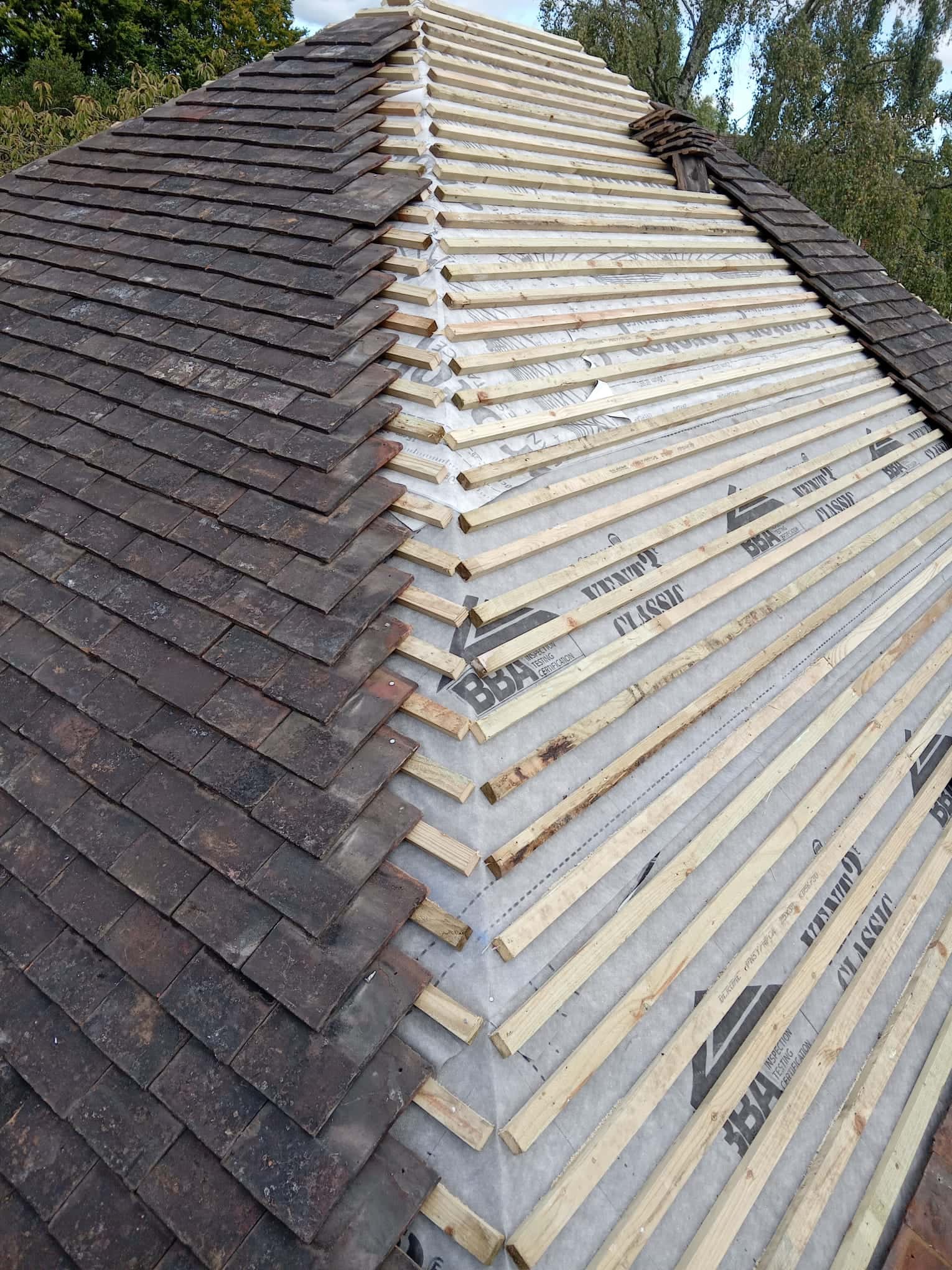 Hipped roof partly re-tiled with new breathable membrane and battens beside the existing roof covering