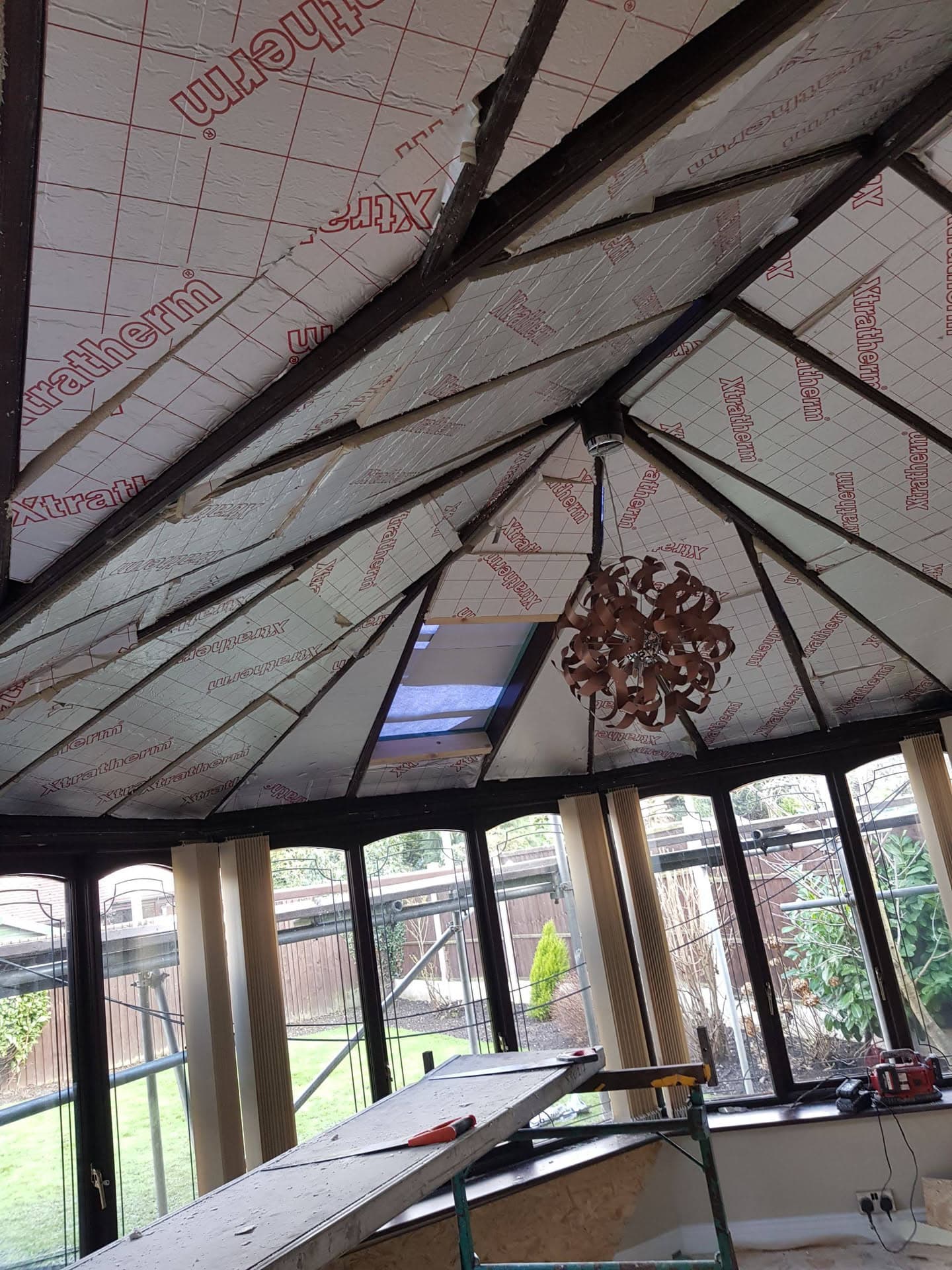 Interior view of conservatory roof during installation showing insulation boards and timber framework