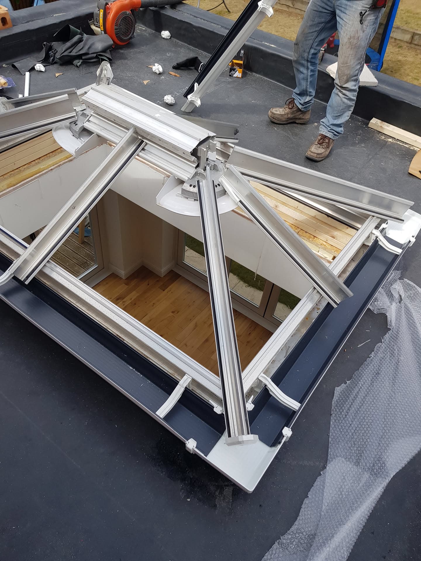 White aluminium roof lantern being installed on flat roof with fitter working