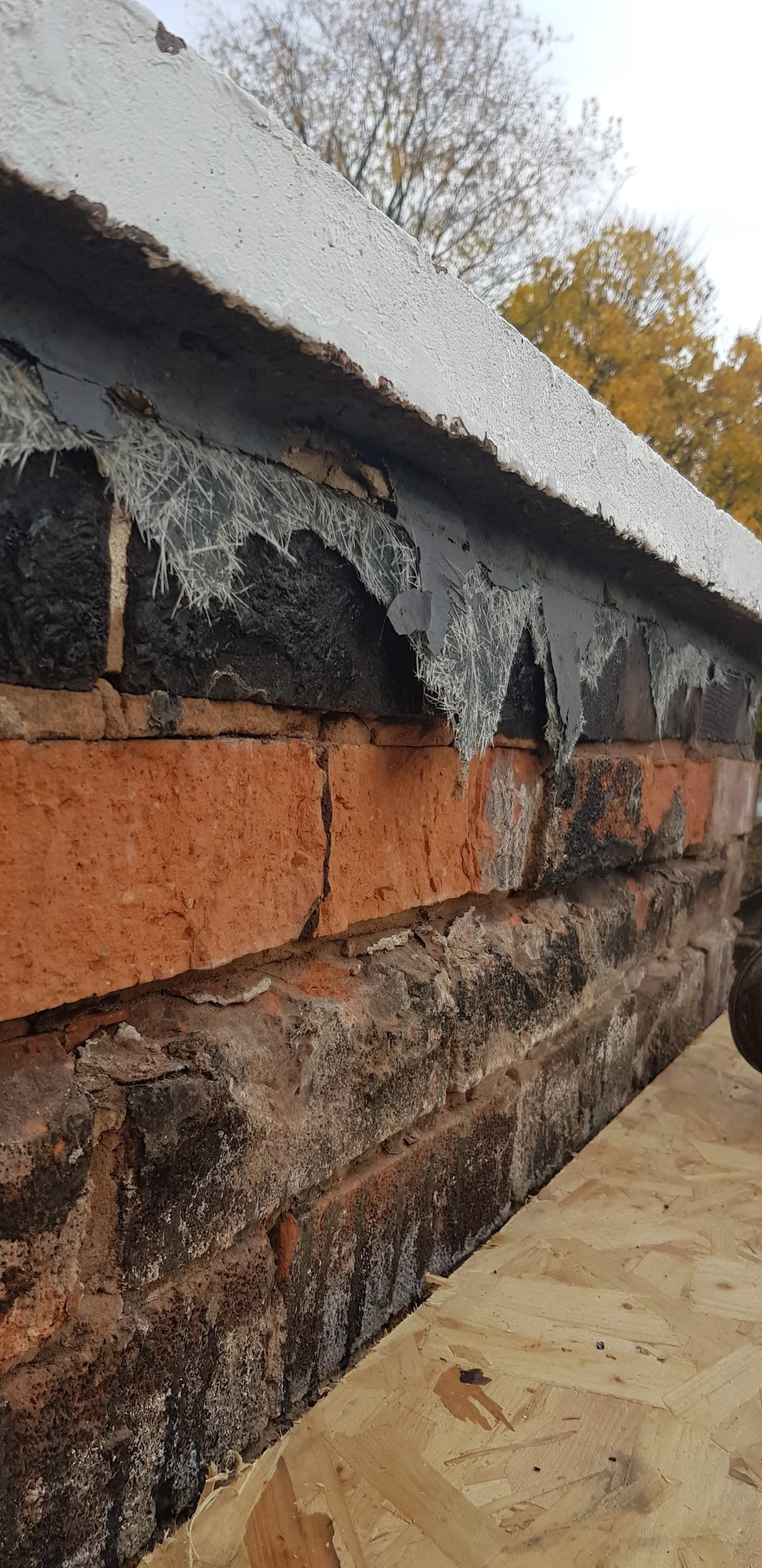 Deteriorated fascia board with cobwebs and damaged brickwork beneath white soffit