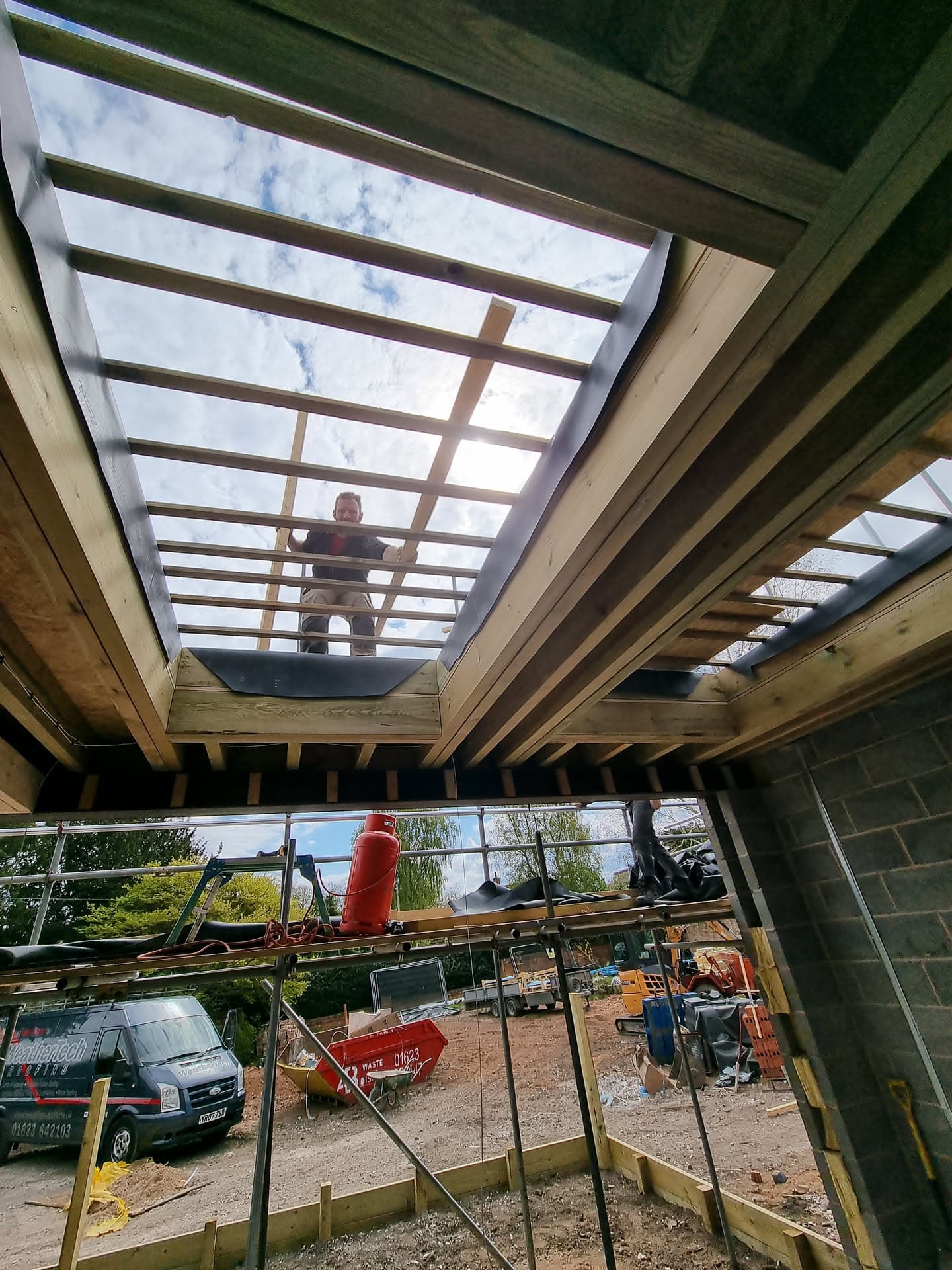 Fitter working on timber frame structure for flat roof extension with skylight opening