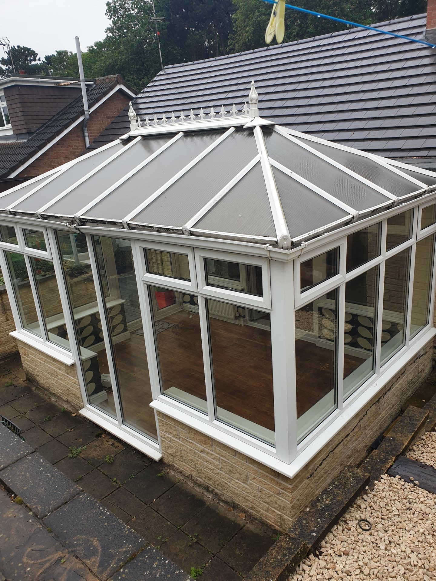 Conservatory with grey solid roof panels and white uPVC frames adjoining dark tiled pitched roof
