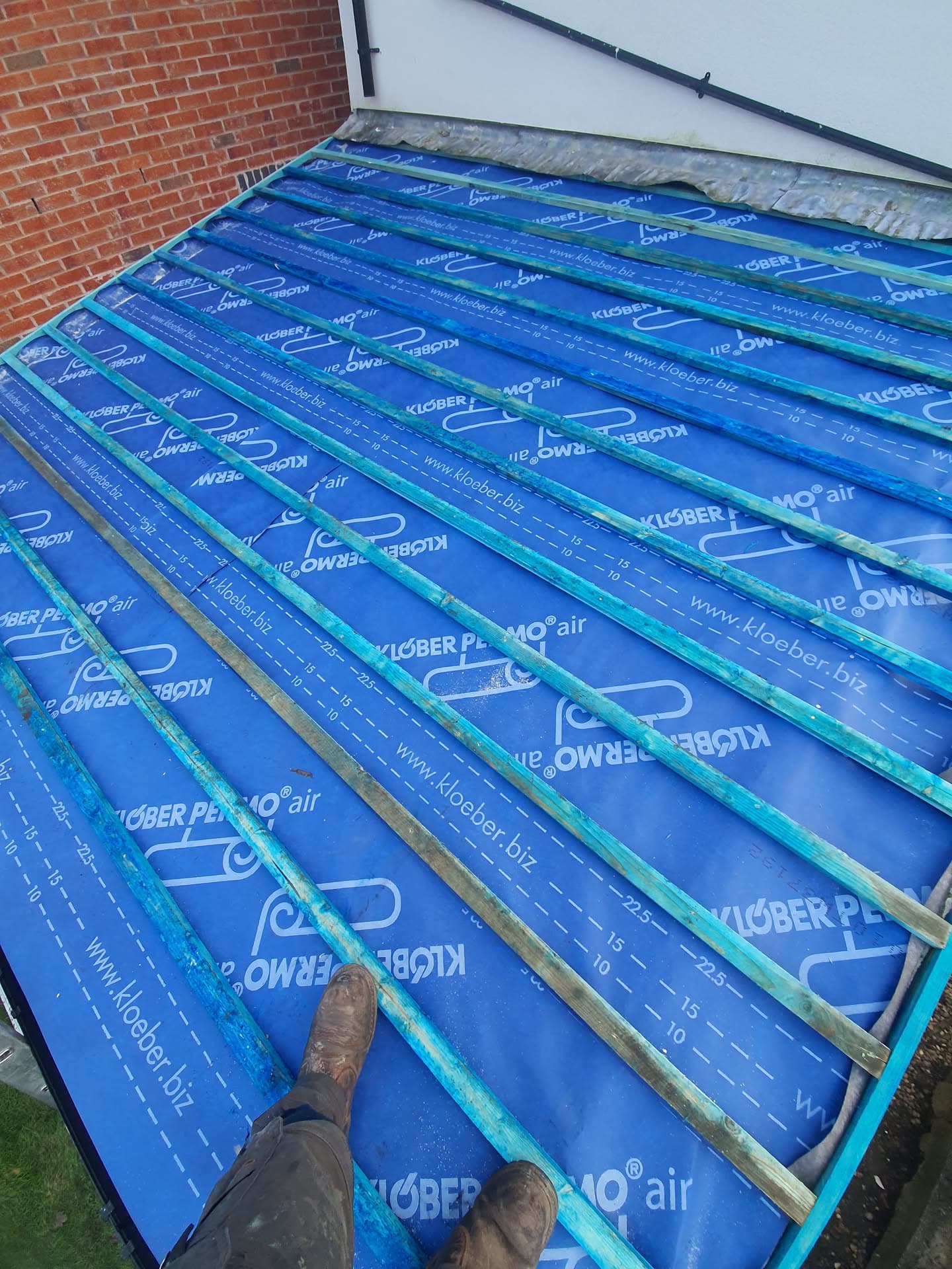 Flat roof installation with blue breathable membrane laid over timber battens