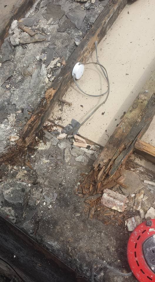 Damaged flat roof surface with deteriorated felt, exposed timber joists and debris