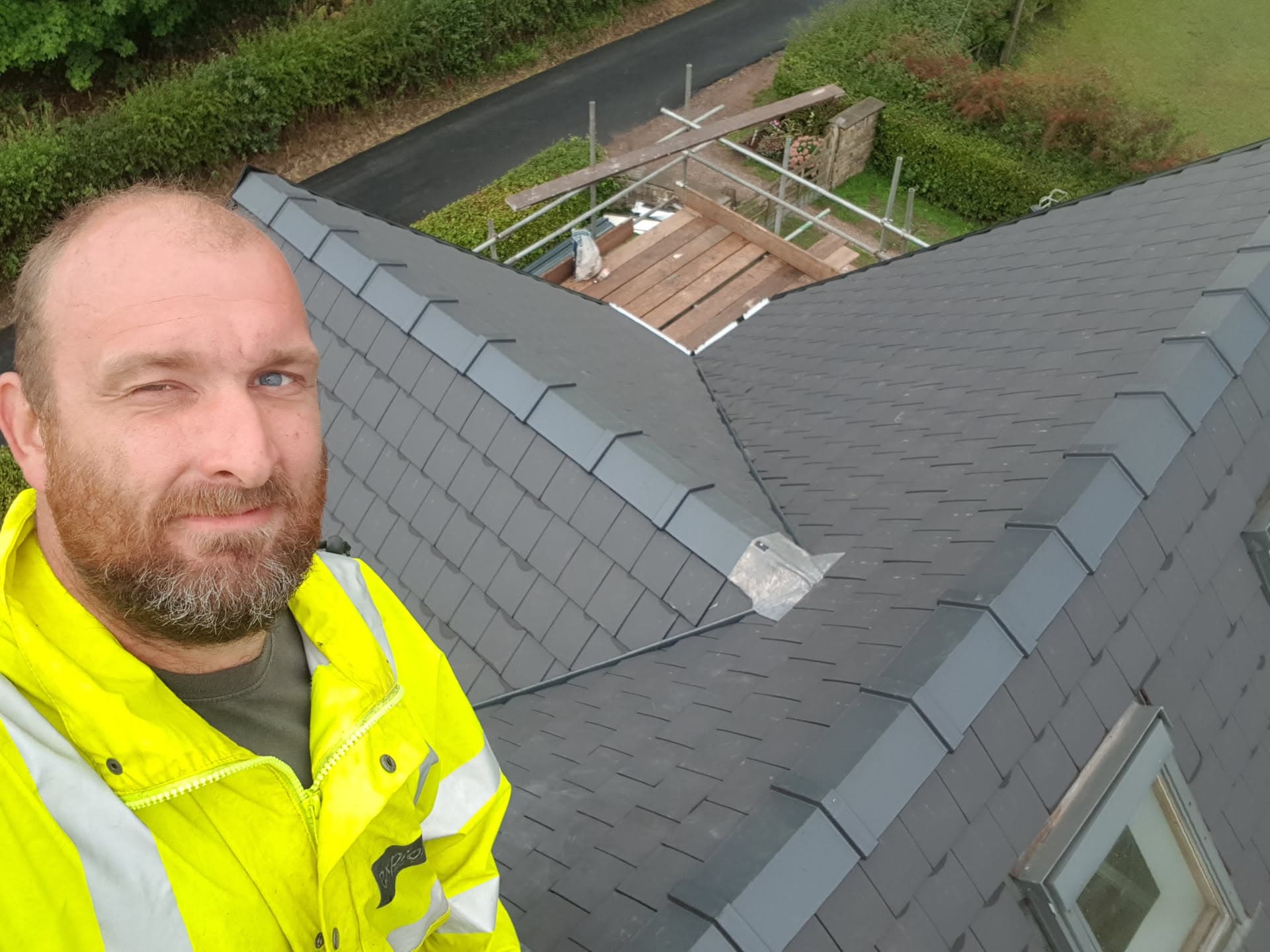 WeatherTech fitter on completed grey slate pitched roof with conservatory frame visible below