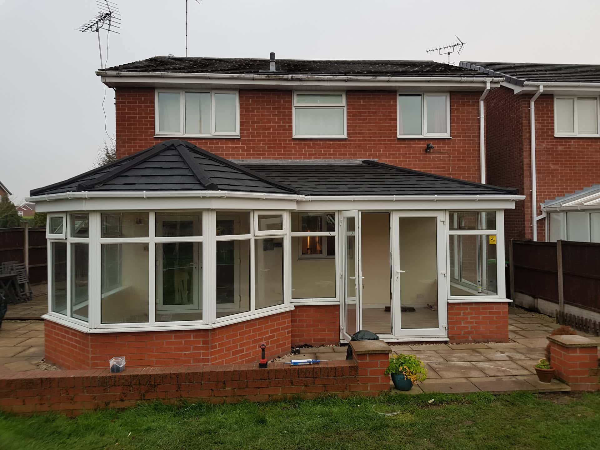 Conservatory with new dark tiled roof and white uPVC frames on brick base