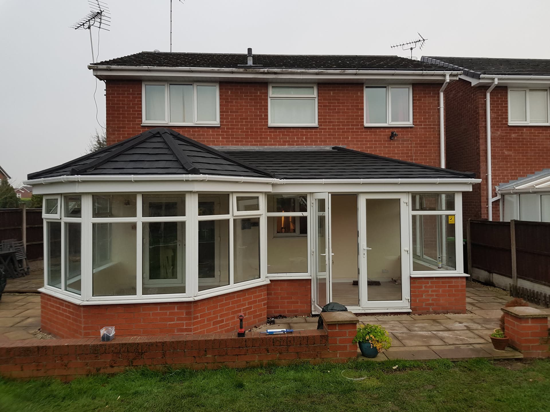 Conservatory with new dark tiled roof and white uPVC frames on brick base