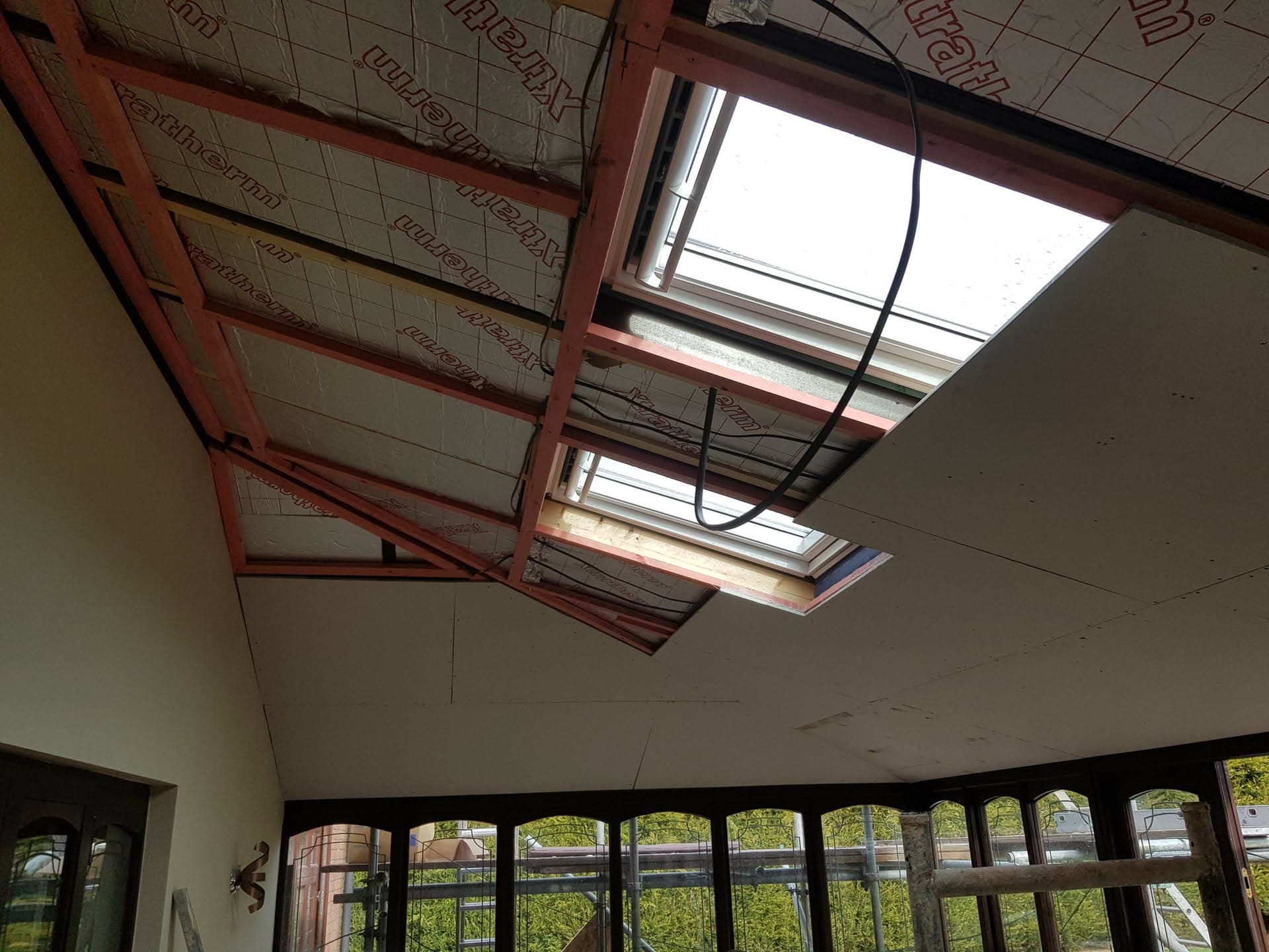 Interior view of conservatory roof installation with exposed timber frame, insulation boards and roof windows
