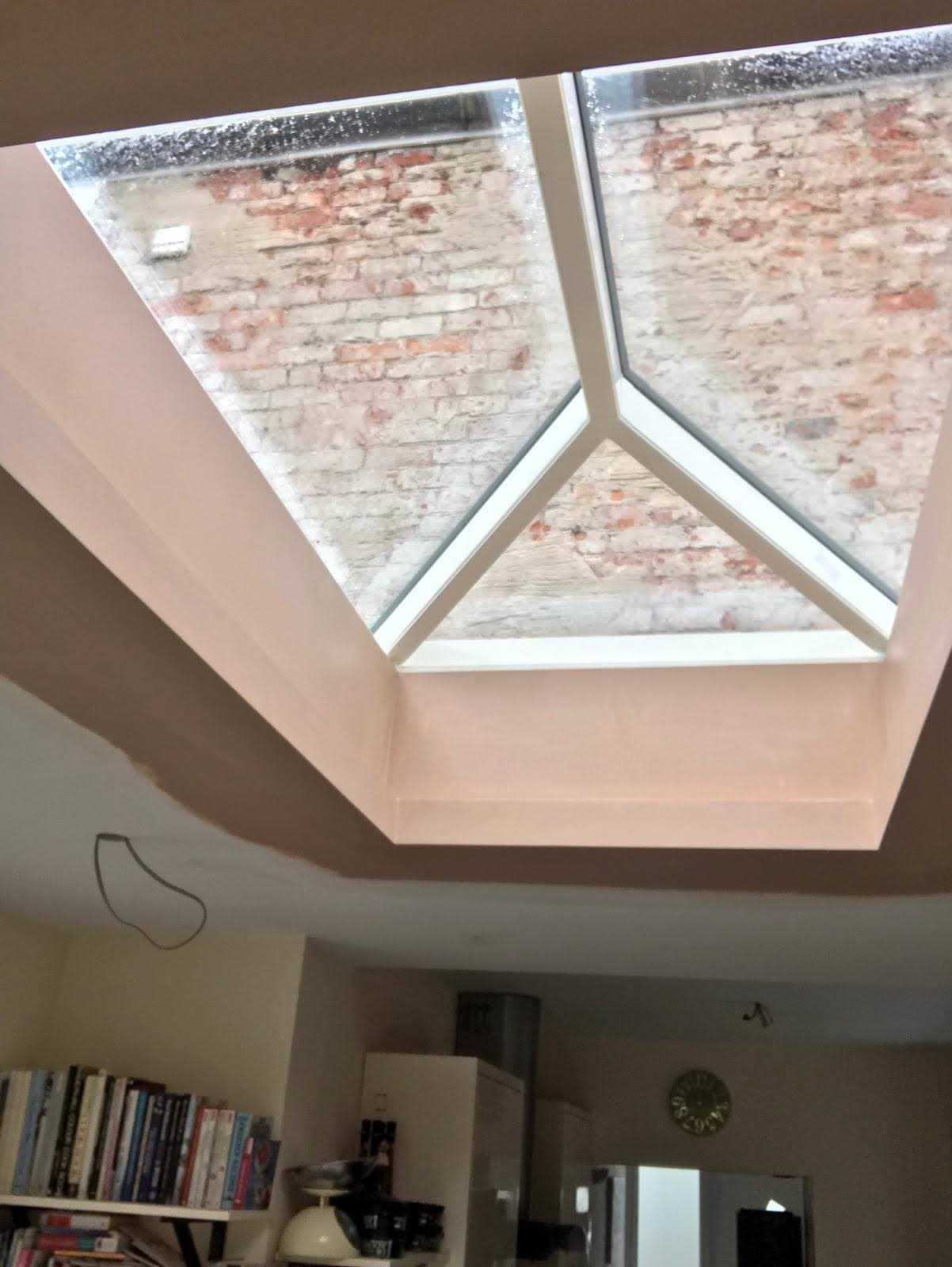 Interior view of lantern roof light with white frame looking up at brick wall