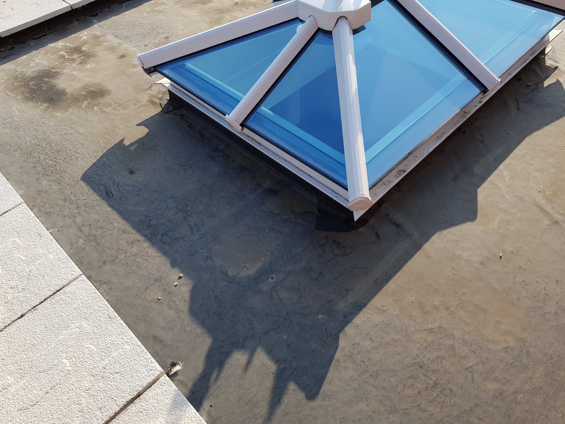 Flat roof with blue glazed pyramid skylight and white aluminium trim