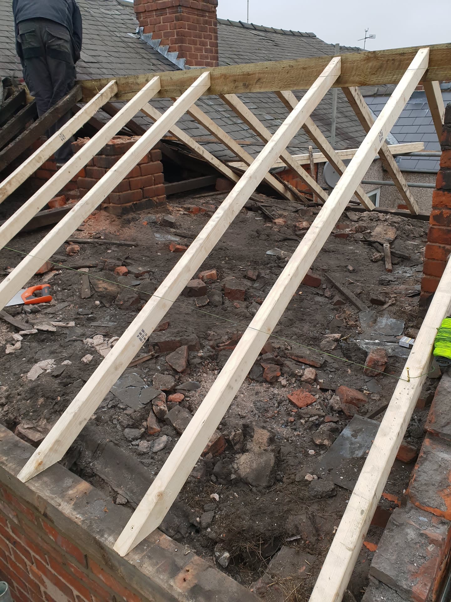 Flat roof rebuild in progress with new timber joists installed and fitter working