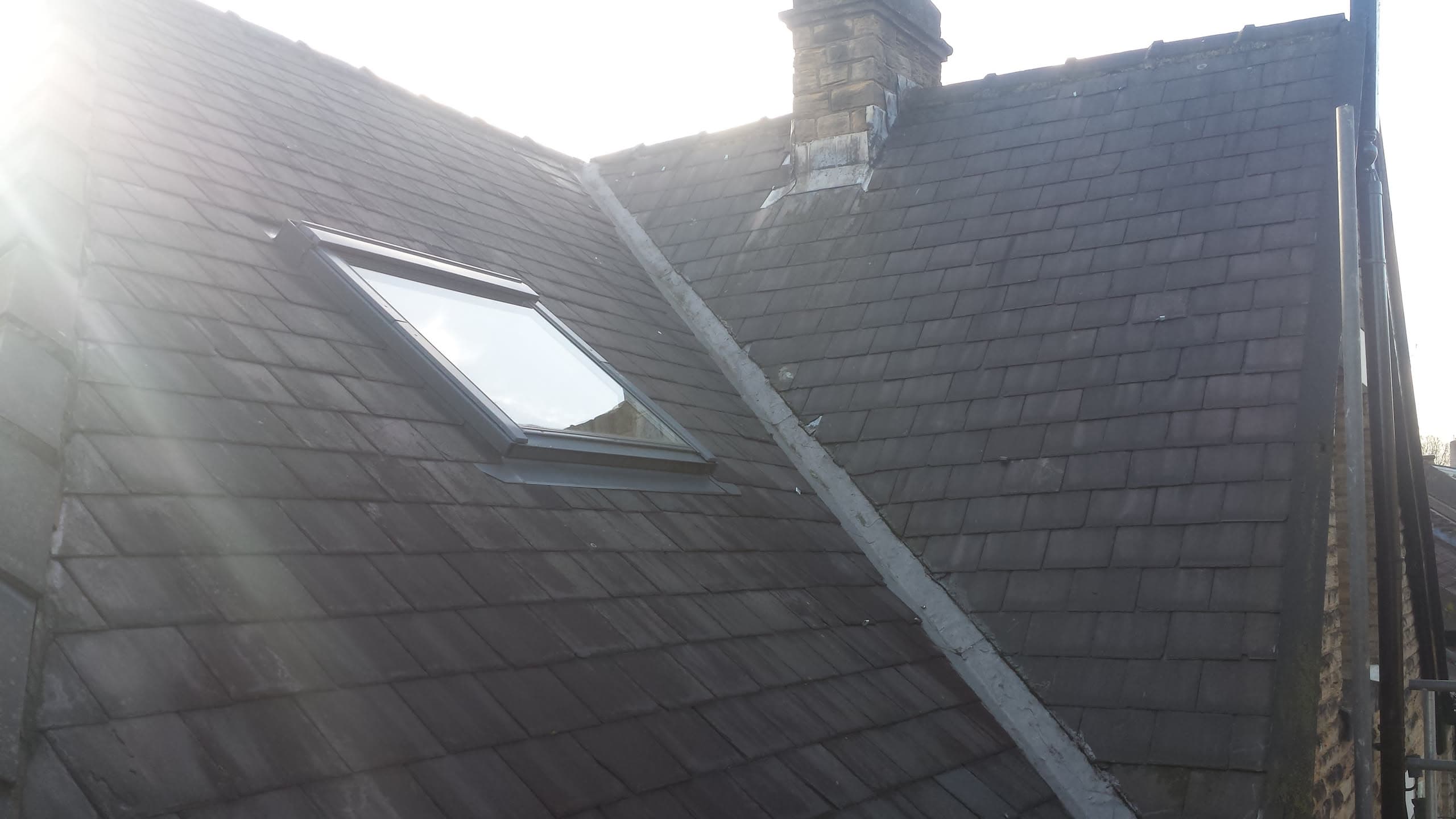 Pitched slate roof with Velux roof window and brick chimney stack
