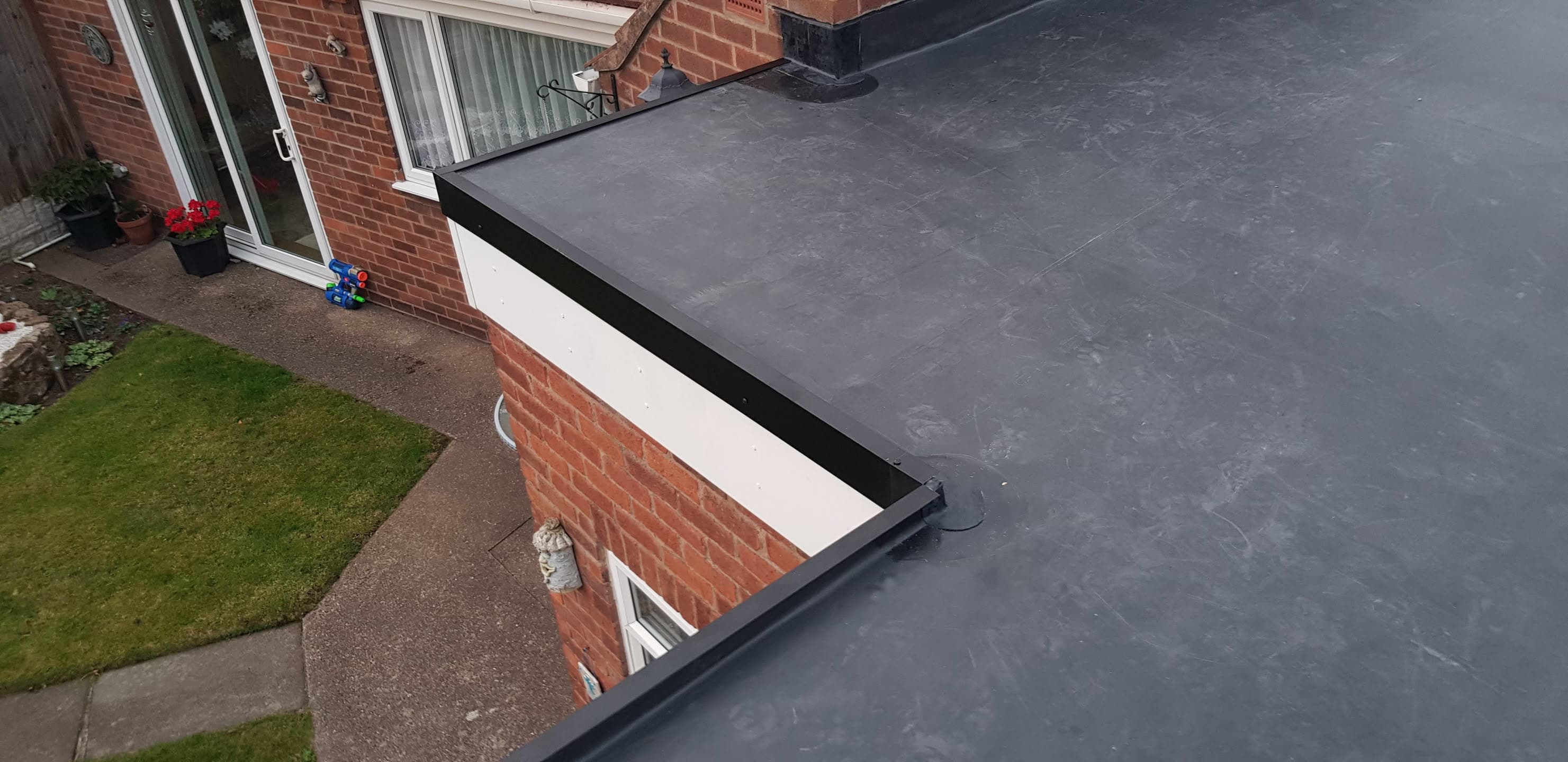 Grey EPDM rubber flat roof with black fascia and trim on residential extension
