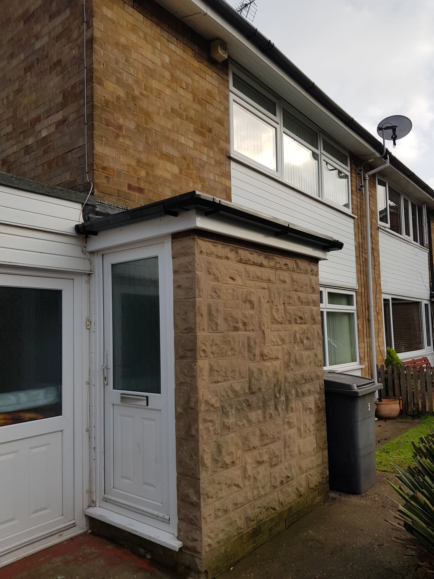 Flat porch roof with black fascia and guttering on residential property
