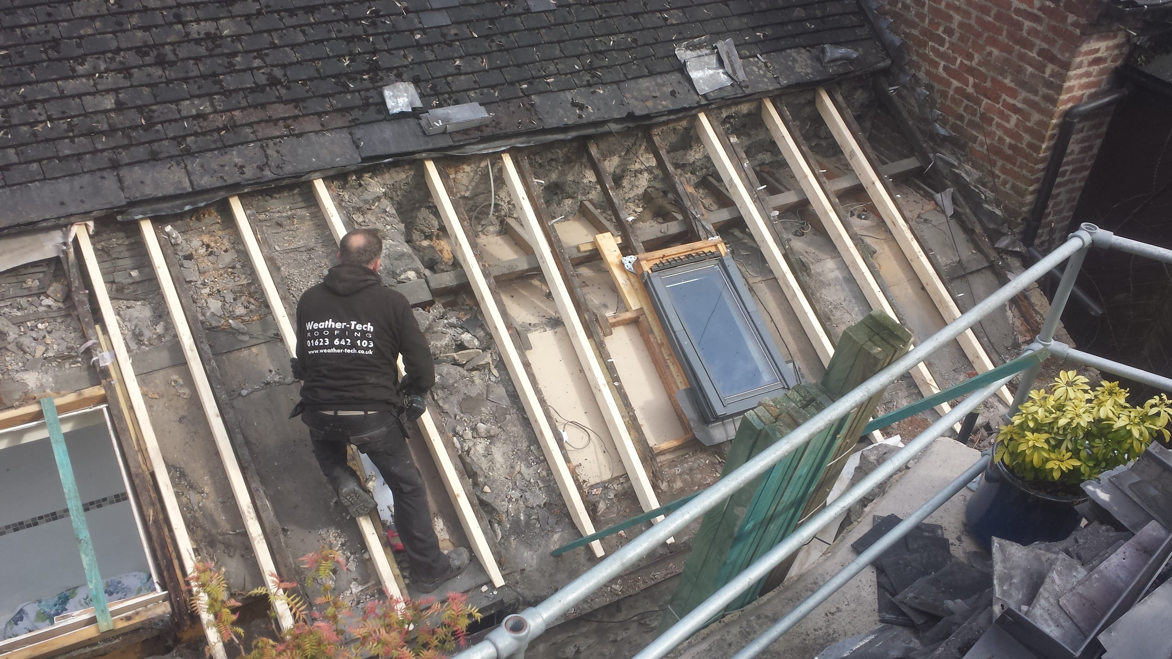WeatherTech fitter working on flat roof with exposed timber joists and skylight
