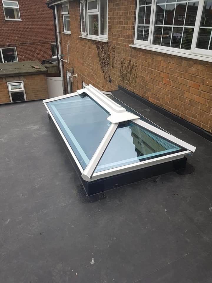 Flat roof with white-framed roof lantern installed on dark felt surface