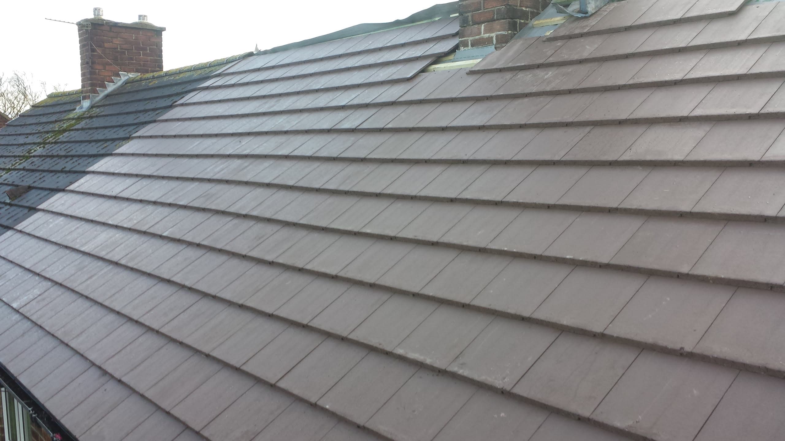 Pitched roof with brown concrete tiles and brick chimney stack