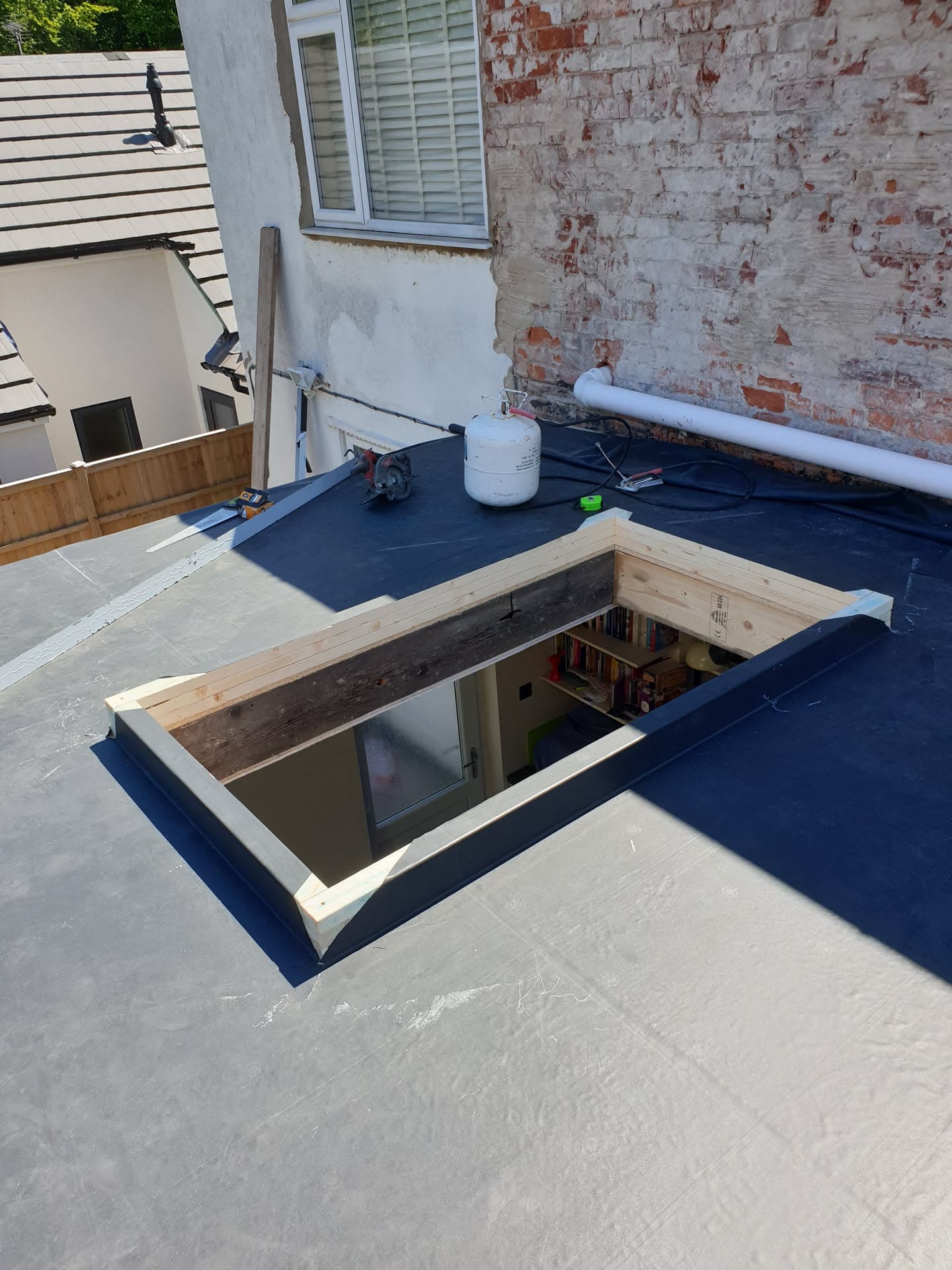 Flat roof with skylight opening showing grey GRP fibreglass surface and timber frame